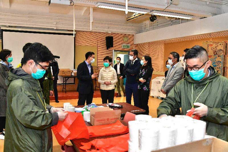 The Chief Executive, Mrs Carrie Lam (fifth right), today (March 25) visited the temporary accommodation at the Sai Kung Outdoor Recreation Centre to encourage the Government staff and volunteers who are managing the site and inspect the accommodation facilities as well as the quarantine units under construction. Photo shows Mrs Lam receiving a briefing on the assistance provided by the Customs and Excise Department volunteer team to the temporary accommodation site. Looking on are the Secretary for Development, Mr Michael Wong (fourth right) and Deputy Director of Leisure and Cultural Services (Leisure Services), Ms Ida Lee (third right).
