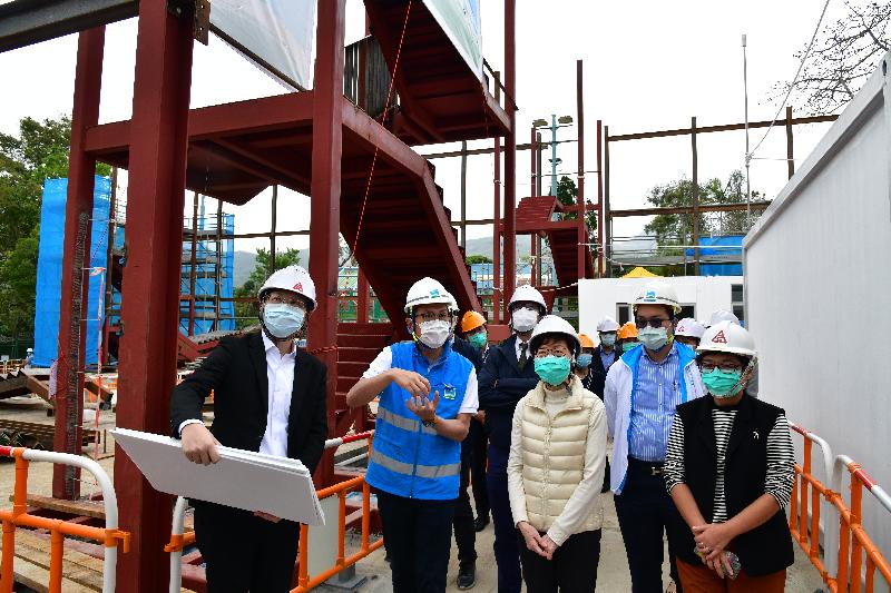 The Chief Executive, Mrs Carrie Lam (third right), today (March 25) visited the temporary accommodation at the Sai Kung Outdoor Recreation Centre to encourage the Government staff and volunteers who are managing the site and inspect the accommodation facilities as well as the quarantine units under construction. Photo shows Mrs Lam inspecting the temporary units built for quarantine purpose at the football pitch of the centre. Looking on are the Secretary for Development, Mr Michael Wong (fourth right) and the Director of Architectural Services, Mrs Sylvia Lam (first right).