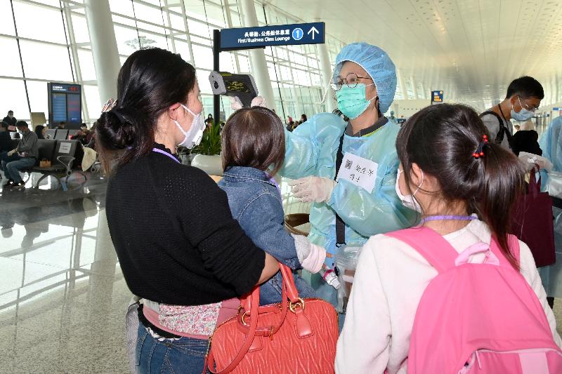 A nurse from the Department of Health conducting temperature checks for a Hong Kong family stranded in Hubei Province before boarding at the Wuhan Tianhe International Airport today (March 25).