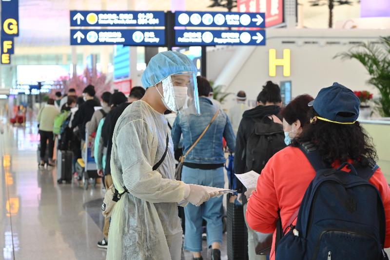 The Hong Kong Special Administrative Region Government today (March 26) continued its operation to bring back Hong Kong residents stranded in Hubei Province by the second batch of chartered flights. Photo shows a staff member of the Immigration Department distributing health declaration forms to Hong Kong residents taking the flight at the Wuhan Tianhe International Airport.