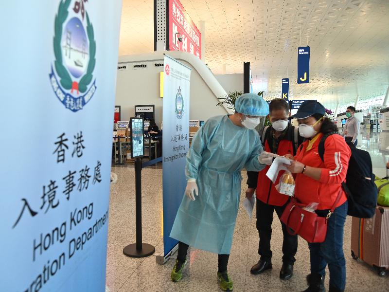A staff member of the Immigration Department assists the Hong Kong residents stranded in Hubei Province to board the chartered flight back to Hong Kong at the Wuhan Tianhe International Airport today (March 26).