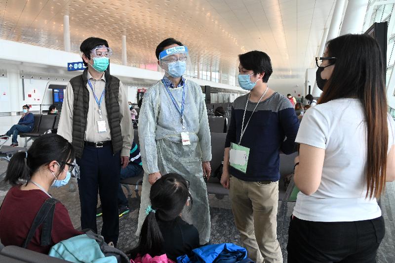 The Secretary for Constitutional and Mainland Affairs, Mr Patrick Nip (second left), and the Director of the Economic and Trade Office in Wuhan, Mr Vincent Fung (first left), send their regards to a family from Enshi who is waiting to board the chartered flight to Hong Kong at the Wuhan Tianhe International Airport today (March 26).
