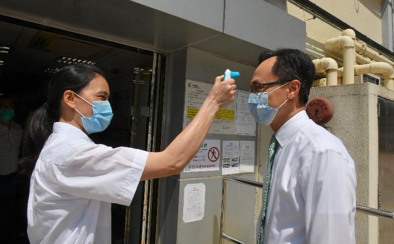 The Secretary for the Civil Service, Mr Patrick Nip, today (April 28) visited a Driving Test Centre in Ho Man Tin to learn more about the preparations made by the Transport Department for the resumption of driving tests, including the epidemic prevention measures implemented at the centre. Photo shows Mr Nip (right), having his temperature checked at the entrance of the centre.
