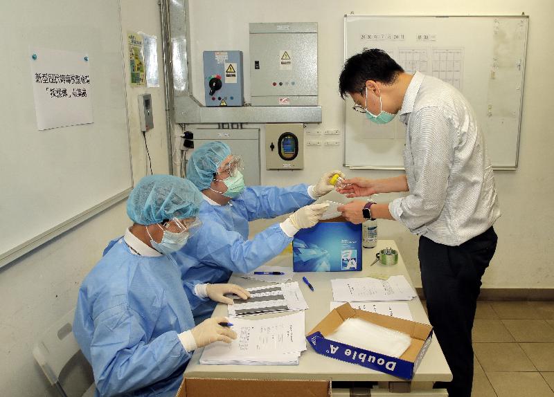 The Home Affairs Department and the Hong Kong Association of Property Management Companies join hands to launch today (July 20) the "Community Testing of COVID-19 for Frontline Property Management Workers". Photo shows staff from a property management company explaining to a worker the procedures of collecting deep throat saliva samples.