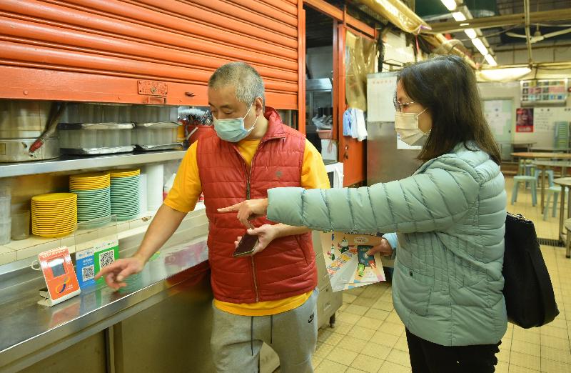 The Deputy Director of Food and Environmental Hygiene, Miss Diane Wong (right), visited Shui Wo Street Market in Kwun Tong today (December 16) to distribute leaflets to market tenants, promoting  contactless payment and reminding them to adopt various anti-epidemic measures and comply with anti-epidemic regulations.