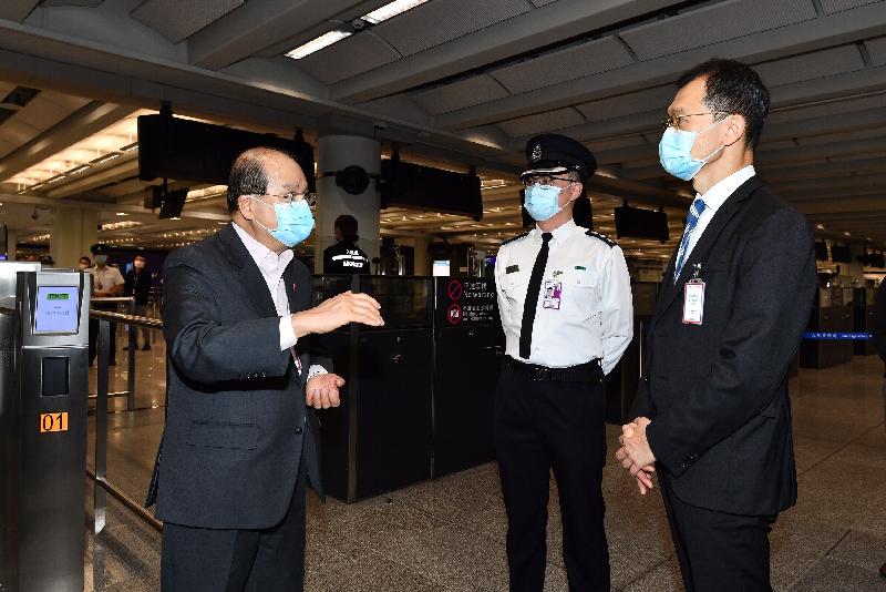 政務司司長張建宗今日（二月十三日）到訪香港國際機場。圖示張建宗（左一）在入境事務處副處長陳天賜（右一）陪同下，與當值的入境事務處前線人員交談，感謝他們在假期期間辛勤工作。