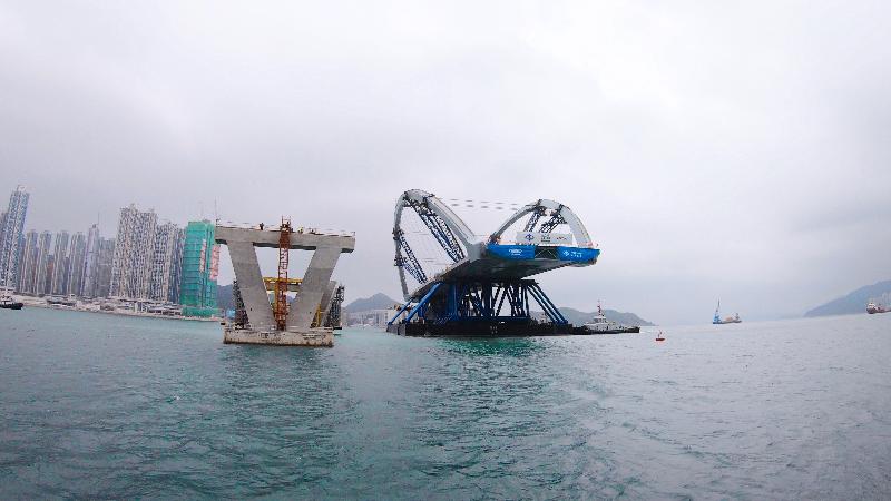 Erection of the prefabricated double-arch steel bridge for the Cross Bay Link, Tseung Kwan O, was completed today (February 26). Photo shows the semi-submersible barge carrying the double-arch steel bridge at a position 30 metres from the bridge piers for final preparation.