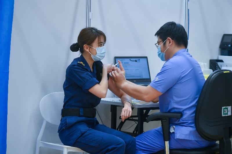 Around 100 people in the vaccination priority groups today (March 8) received the Comirnaty vaccine at the Community Vaccination Centre at the Sun Yat Sen Memorial Park Sports Centre. Photo shows an officer of the Customs and Excise Department (left) being vaccinated.