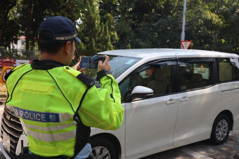 香港警務處將於二○二一年三月十六日擴展「電子定額罰款通知書先導計劃」，應用於發出違例行車告票。圖示警務人員於現場拍攝相片，以記錄違例情況作為取證之用。