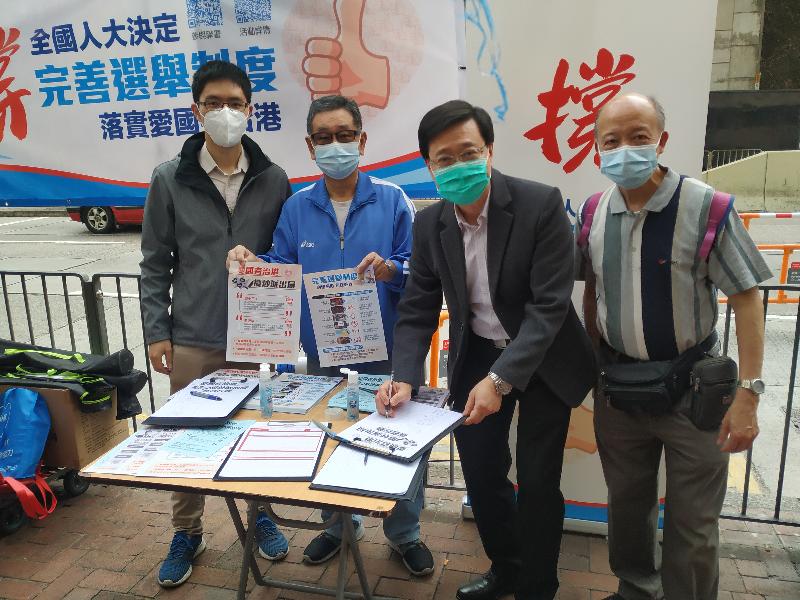 The Secretary for Security, Mr John Lee (third left), today (March 11) signs at a street counter to support the adoption of the Decision of the National People’s Congress (NPC) on improving the electoral system of the Hong Kong Special Administrative Region by the NPC, implementing the "patriots administering Hong Kong" principle.
