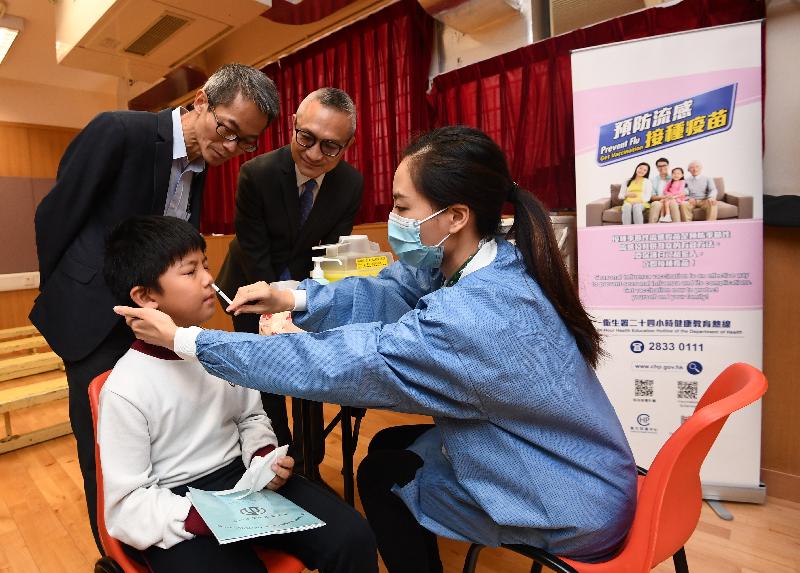 The Under Secretary for Food and Health, Dr Chui Tak-yi (back row, right), and the Controller of the Centre for Health Protection of the Department of Health, Dr Wong Ka-hing (back row, left), visit St Eugene de Mazenod Oblate Primary School today (November 20) to observe pupils receiving seasonal influenza vaccination arranged by the University of Hong Kong's School of Public Health on the campus.