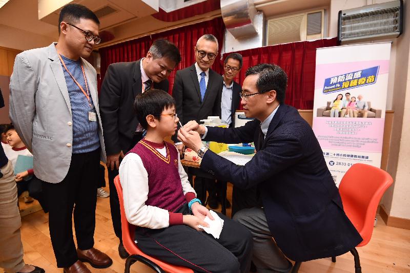 The Clinical Associate Professor and Division Head of the Division of Community Medicine and Public Health Practice of the University of Hong Kong's School of Public Health, Dr Dennis Ip (front row, right), administers a nasal influenza vaccine for a student at St Eugene de Mazenod Oblate Primary School today (November 20). Looking on (back row, from left) are the Chairman of the Parent-Teacher Association, Mr Fred Chan; the Principal, Mr Yip Chi Shing; the Under Secretary for Food and Health, Dr Chui Tak-yi; and the Controller of the Centre for Health Protection of the Department of Health, Dr Wong Ka-hing.