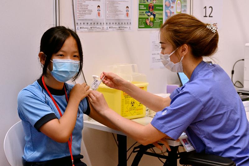 About 20 students, parents, teachers and school staff from Fanling Government Primary School received a COVID-19 vaccine at the Community Vaccination Centre at Lung Sum Avenue Sports Centre through group booking this afternoon (June 21). Photo shows a student receiving her COVID-19 vaccination.