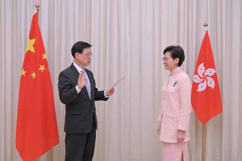The new Chief Secretary for Administration, Mr John Lee Ka-chiu (left), takes the oath of office, witnessed by the Chief Executive, Mrs Carrie Lam (right), today (June 25).