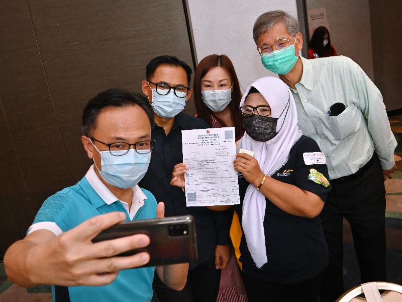 The Secretary for the Civil Service, Mr Patrick Nip, and the Secretary for Labour and Welfare, Dr Law Chi-kwong, viewed the administering of the Sinovac vaccine to Indonesians staying in Hong Kong by the Government's outreach vaccination team at a hotel in Causeway Bay today (August 1). Photo shows Mr Nip (first left), Dr Law (first right) and the Consul General of the Republic of Indonesia in Hong Kong, Mr Ricky Suhendar (second left) taking a selfie with an Indonesian (second right) after vaccination.