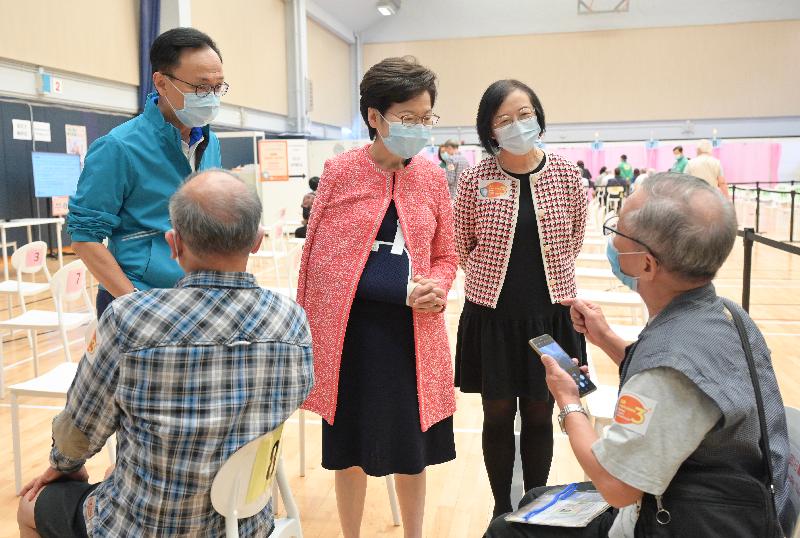 The Chief Executive, Mrs Carrie Lam, today (November 11) received her third dose of the Sinovac vaccine at the Community Vaccination Centre at Java Road Sports Centre. Photo shows Mrs Lam (centre), accompanied by the Secretary for the Civil Service, Mr Patrick Nip (first left), and the Secretary for Food and Health, Professor Sophia Chan (second right), chatting with members of the public who received vaccination at the centre.