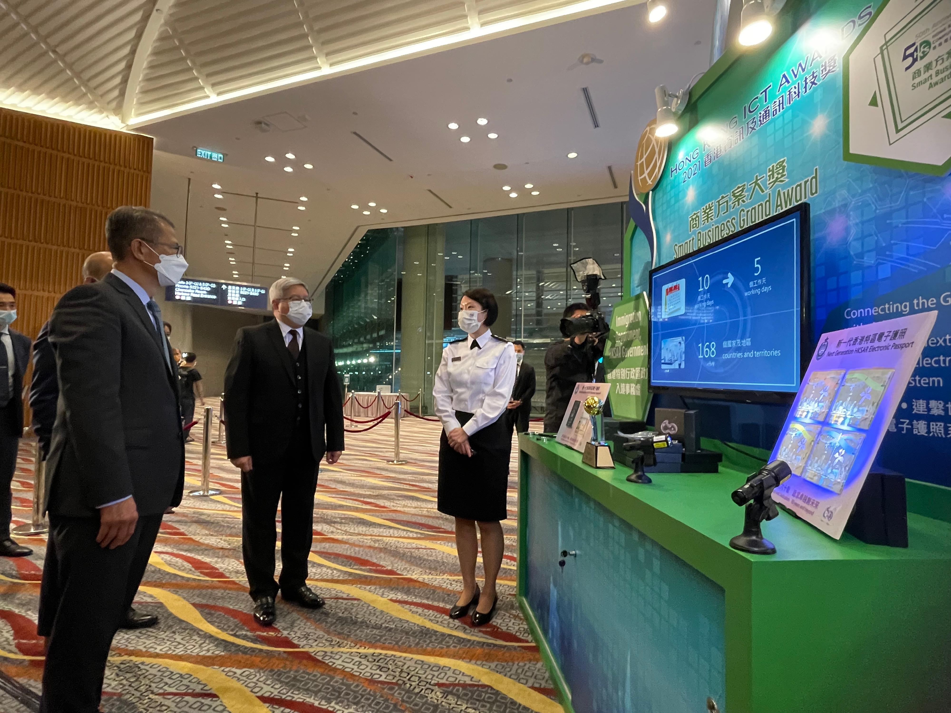 The Director of Immigration, Mr Au Ka-wang (centre), accompanies the Financial Secretary, Mr Paul Chan (left) at the Hong Kong ICT Awards 2021 Awards Presentation Ceremony this evening (November 29) to listen to an Immigration officer introducing the Next Generation Electronic Passport System.