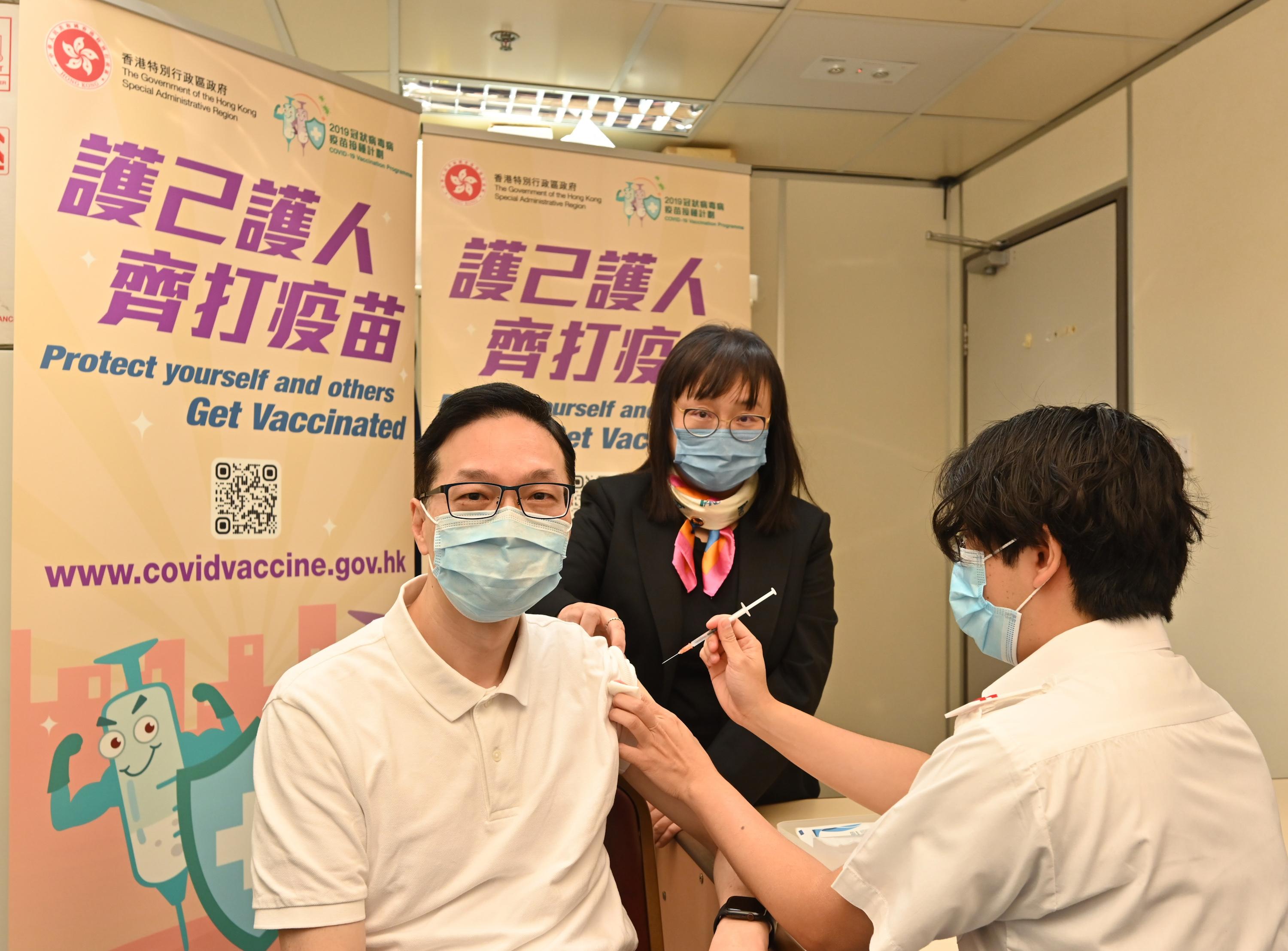 衞生署助理署長（藥物）陳凌峯（左）今日（十二月二日）於衞生署診所接種第三劑新冠疫苗（克爾來福）。旁為護士總監馮瑪莉博士（中）。