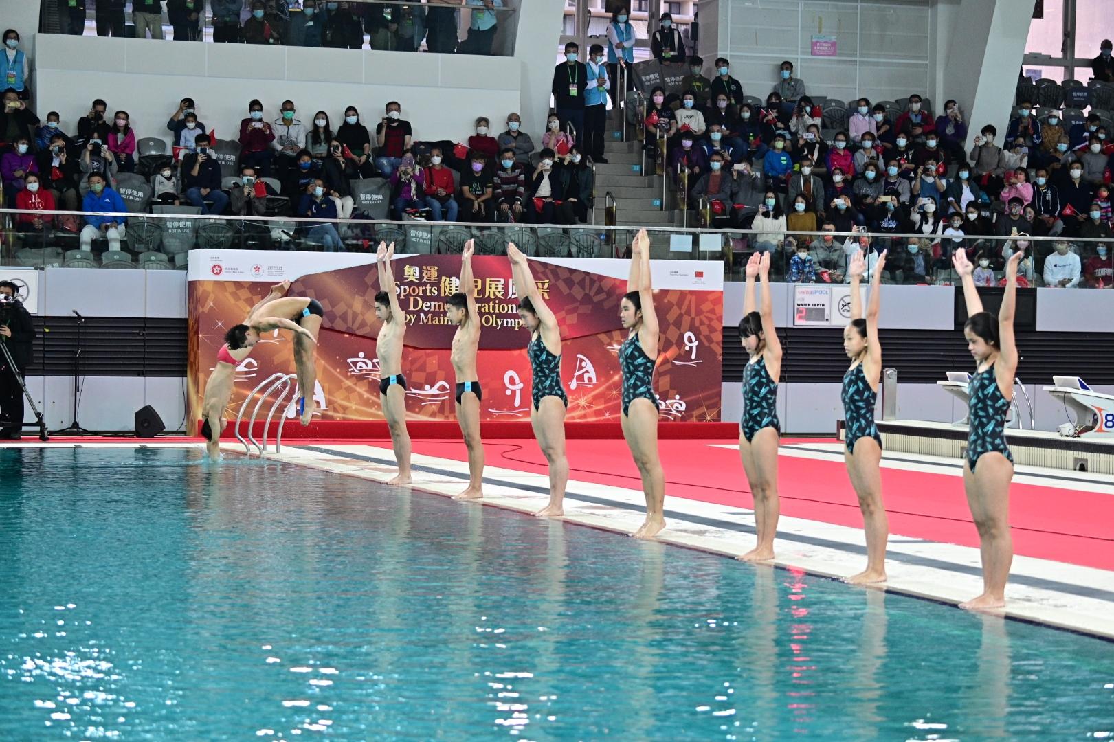 The delegation of Tokyo 2020 Olympic Games Mainland Olympians attended the sports demonstrations at Victoria Park Swimming Pool this morning (December 4). Photo shows Mainland diving athlete Wang Zongyuan (first left) and Hong Kong young athletes performing a spectacular dive.