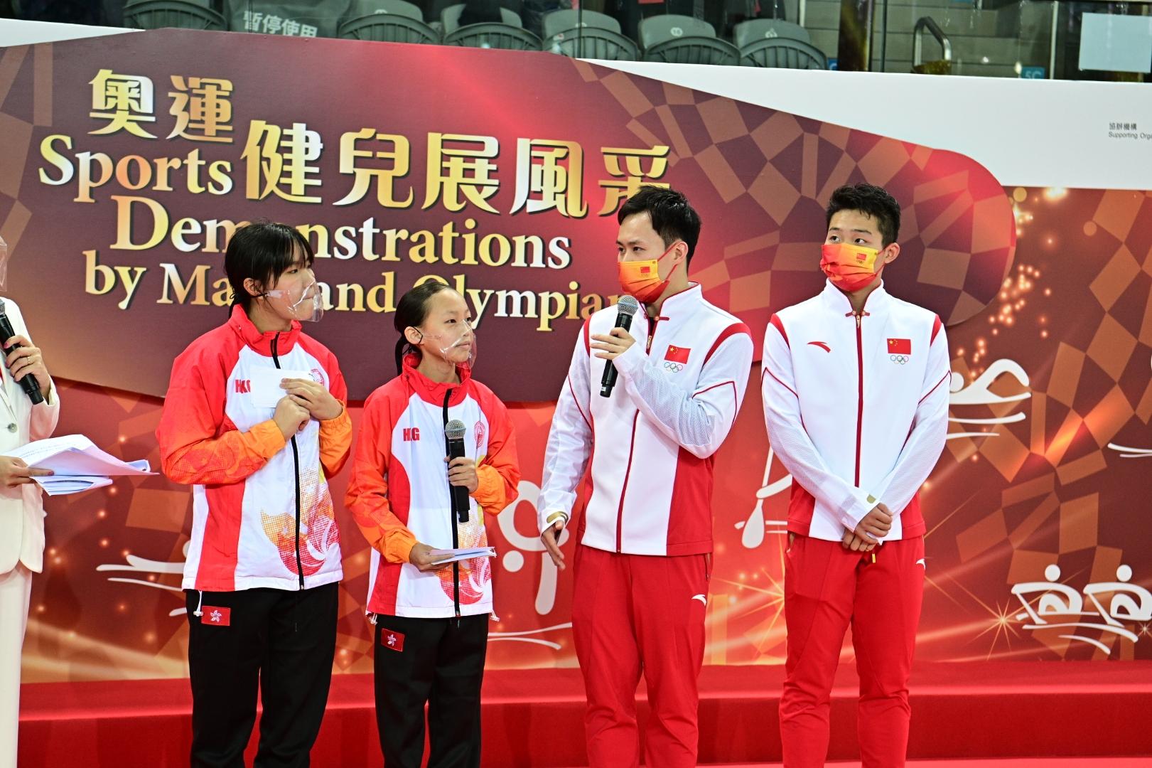 The delegation of Tokyo 2020 Olympic Games Mainland Olympians attended the sports demonstrations at Victoria Park Swimming Pool this morning (December 4). Photo shows Mainland diving athletes Wang Zongyuan (first right) and Xie Siyi (second right) having a chat and skill exchange with local young athletes.