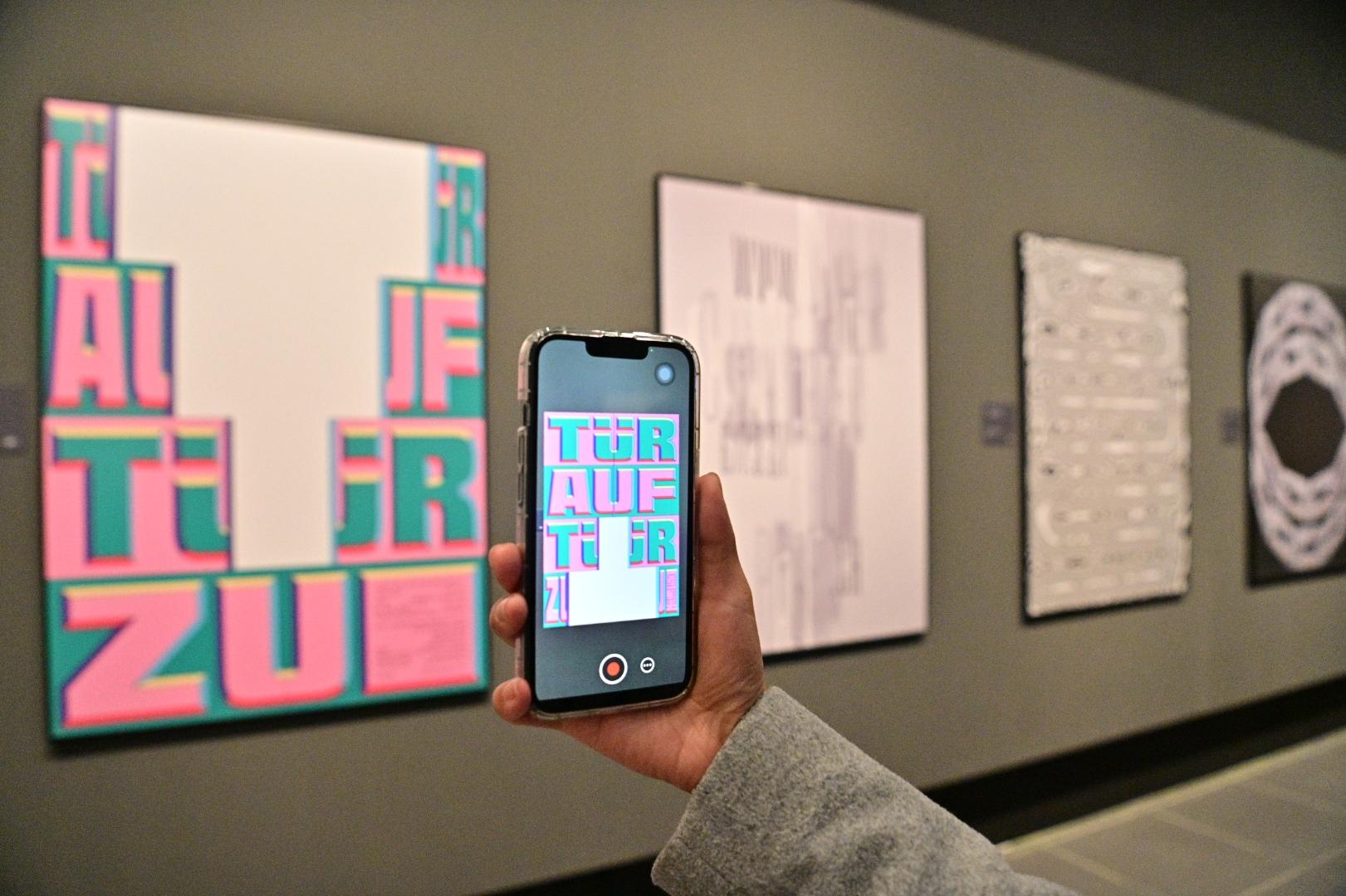 The opening ceremony for the "Still & Motion - Hong Kong International Poster Triennial 2021" exhibition was held today (December 13) at the Hong Kong Heritage Museum. Photo shows a visitor using the augmented reality (AR) mobile app to view the impact of poster animations through a smartphone.