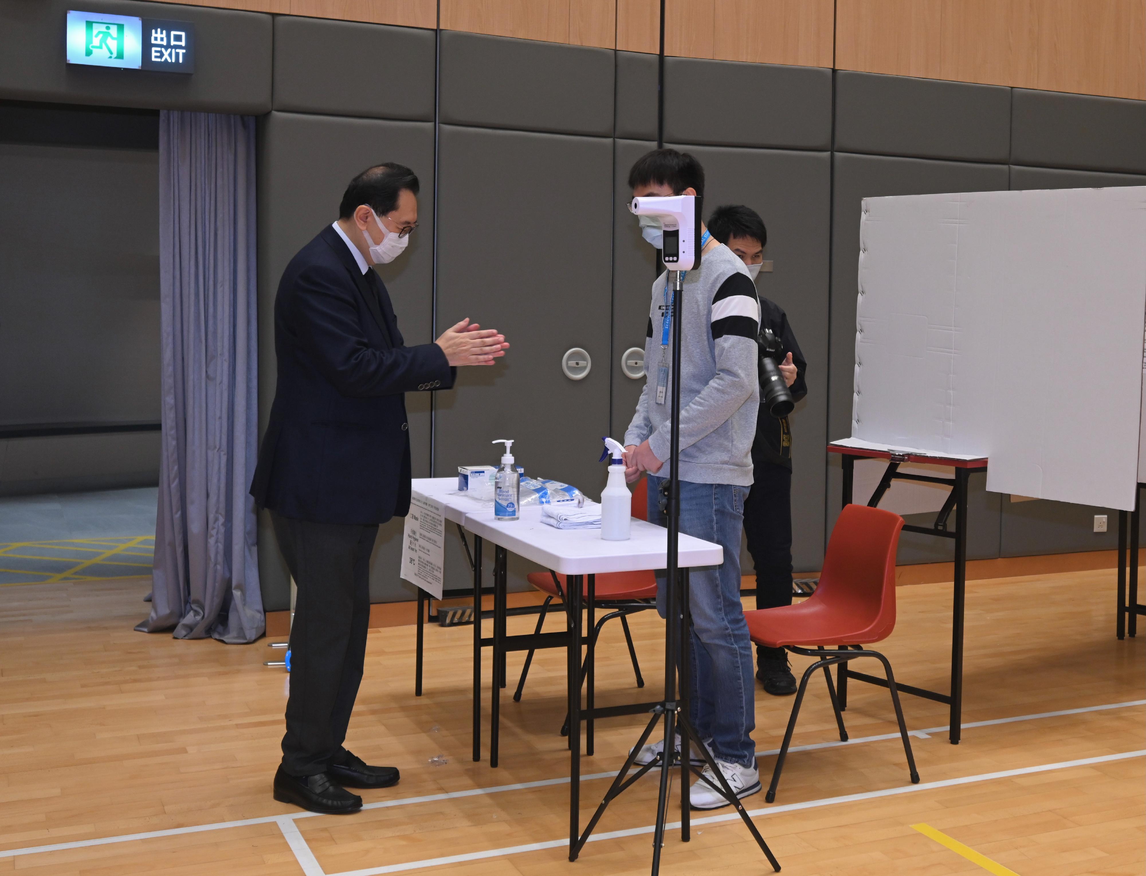 The Chairman of the Electoral Affairs Commission, Mr Justice Barnabas Fung Wah (first left), demonstrates the proper procedure to cast votes in the Legislative Council General Election during his visit to a mock polling station at the North Point Community Hall today (December 14).