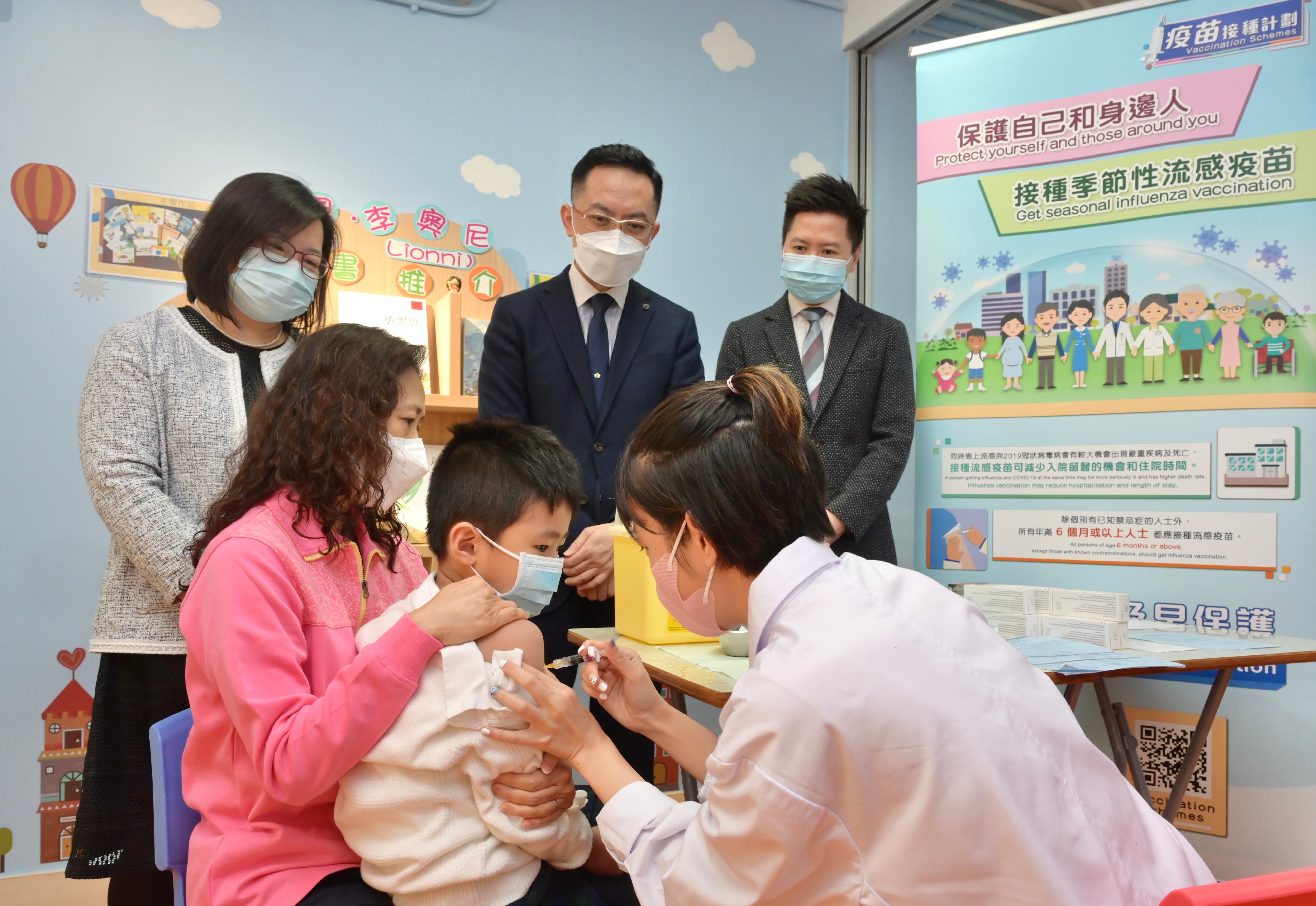The Director of Health, Dr Ronald Lam, and the Controller of the Centre for Health Protection of the Department of Health, Dr Edwin Tsui, this morning (December 15) visited St Thomas' Church Kindergarten in Shek Kip Mei to view the implementation of the school outreach seasonal influenza vaccination service. Photo shows Dr Lam (back row, centre) and Dr Tsui (back row, right) watching a pupil receive vaccination.