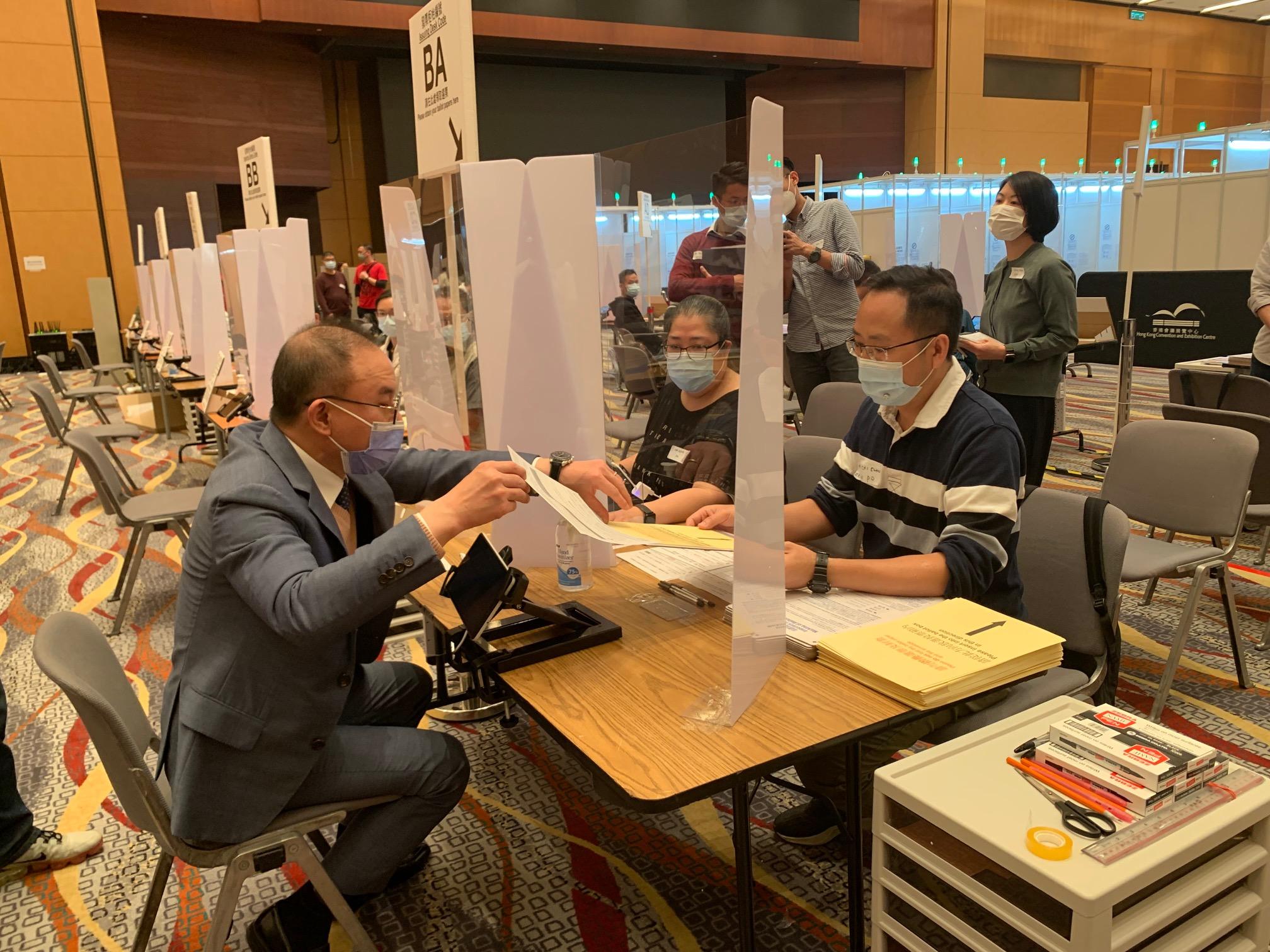 The Secretary for Constitutional and Mainland Affairs, Mr Erick Tsang Kwok-wai, today (December 18) visited the central counting station and Election Committee constituency (ECC) polling station at the Hong Kong Convention and Exhibition Centre. Photo shows Mr Tsang (left) being briefed by electoral staff on the operation of ballot paper issuing desks at the ECC polling station.