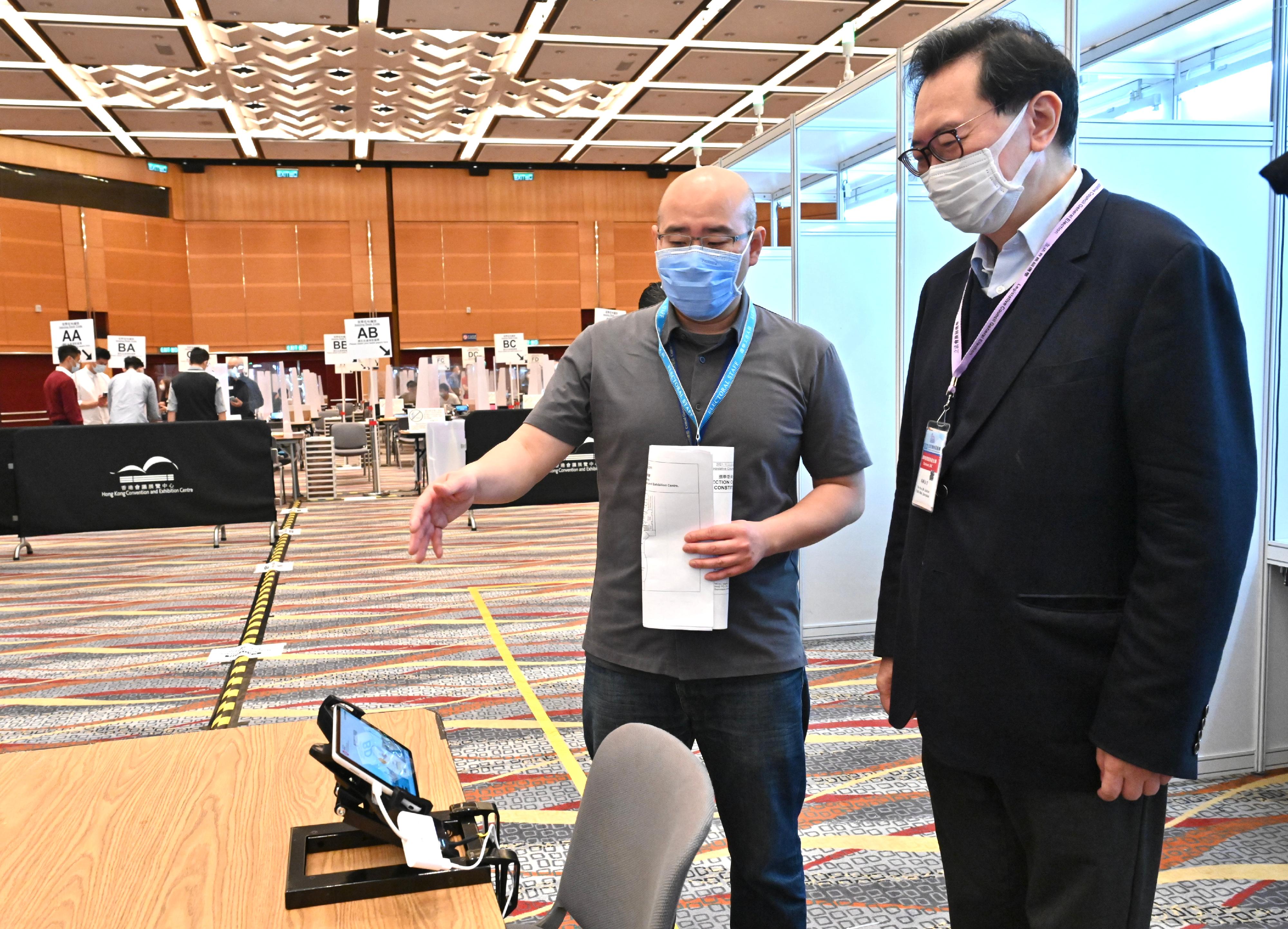 The Chairman of the Electoral Affairs Commission, Mr Justice Barnabas Fung Wah (right), visits the Election Committee Constituency polling station of the 2021 Legislative Council General Election at the Hong Kong Convention and Exhibition Centre this morning (December 18) to inspect the preparatory work. He is briefed by the Presiding Officer. 
