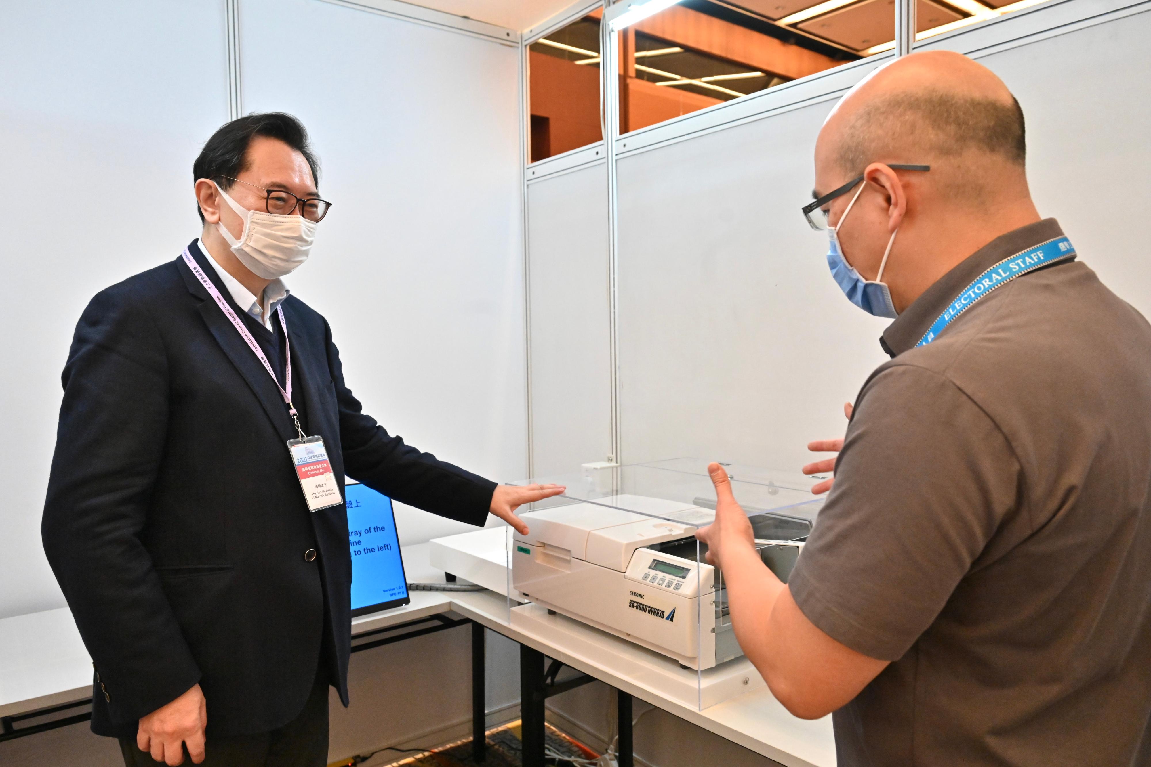 The Chairman of the Electoral Affairs Commission, Mr Justice Barnabas Fung Wah (left), visits the Election Committee Constituency polling station of the 2021 Legislative Council General Election at the Hong Kong Convention and Exhibition Centre this morning (December 18) to inspect the preparatory work. He is briefed by the Presiding Officer on the operation of Optical Mark Recognition machines.

