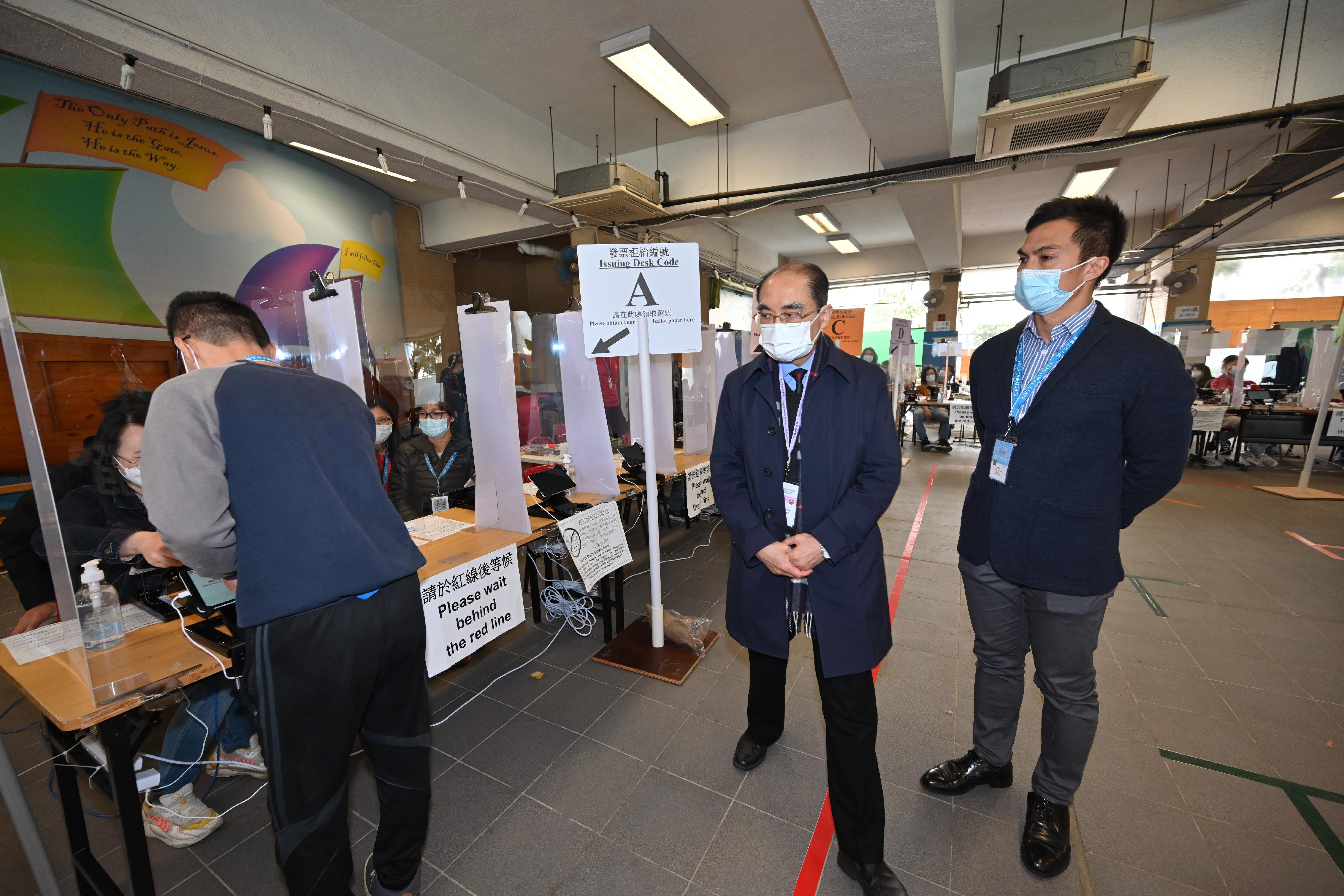 Electoral Affairs Commission member Mr Arthur Luk, SC (centre), visits the polling station of the 2021 Legislative Council General Election at Yaumati Catholic Primary School (Hoi Wang Road) today (December 18) to inspect the electoral preparation work.