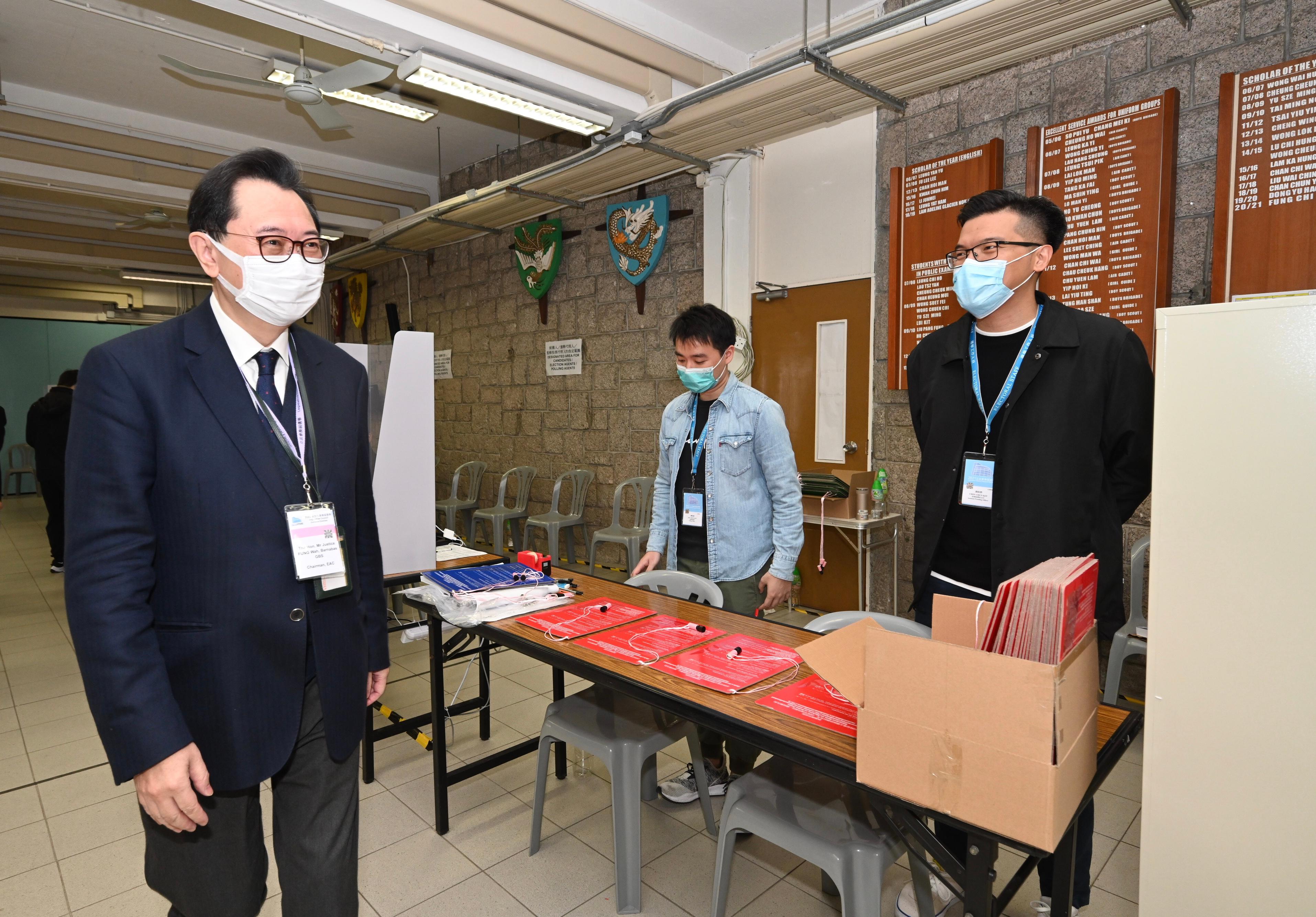 The Chairman of the Electoral Affairs Commission, Mr Justice Barnabas Fung Wah (left) visits the polling station at Jockey Club Government Secondary School today (December 19) to inspect the operation of the polling station of the 2021 Legislative Council General Election.