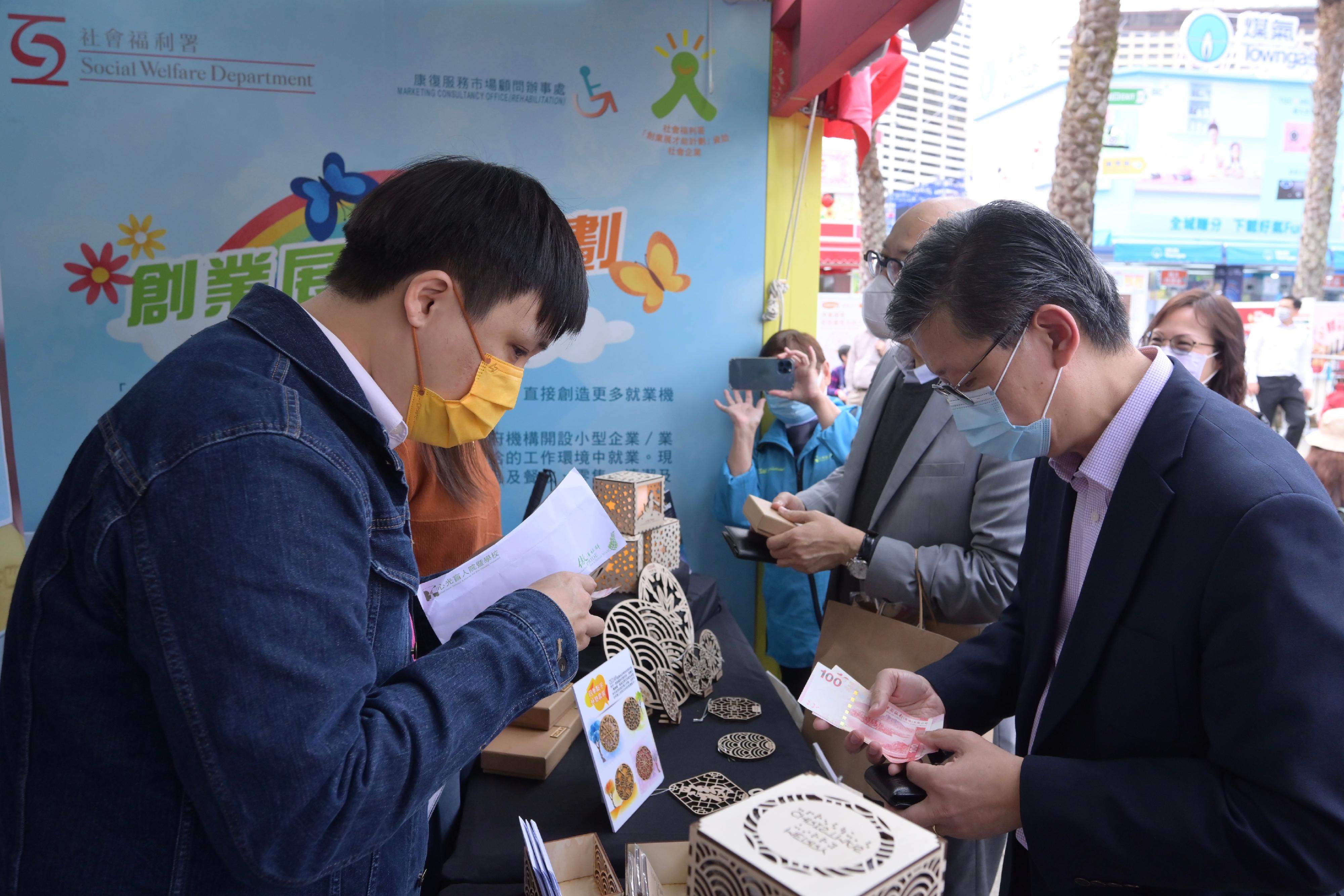 The Director of Social Welfare, Mr Gordon Leung, and the Chairperson of the Advisory Committee on Enhancing Employment of People with Disabilities, Dr Kevin Lau, visited the 55th Hong Kong Brands and Products Expo at Victoria Park today (December 22). Photo shows Mr Leung (first right) shopping at a booth set up by a rehabilitation service unit.