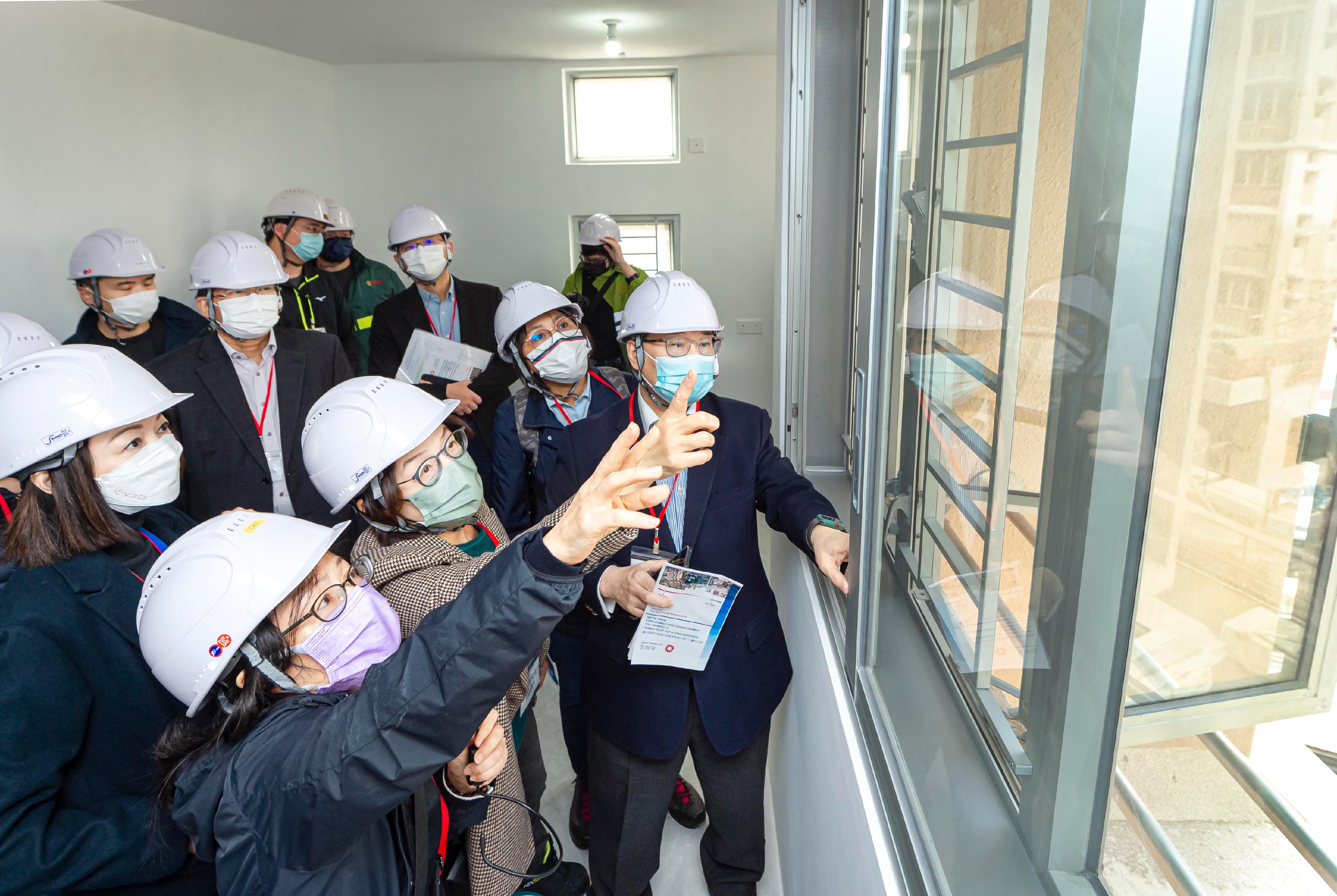 香港房屋委员会及其辖下建筑小组委员会和投标小组委员会的委员今日（十二月二十三日）视察钻石山居者有其屋项目启翔苑，了解项目的进展。图示委员听取有关样板房减音窗的讲解。