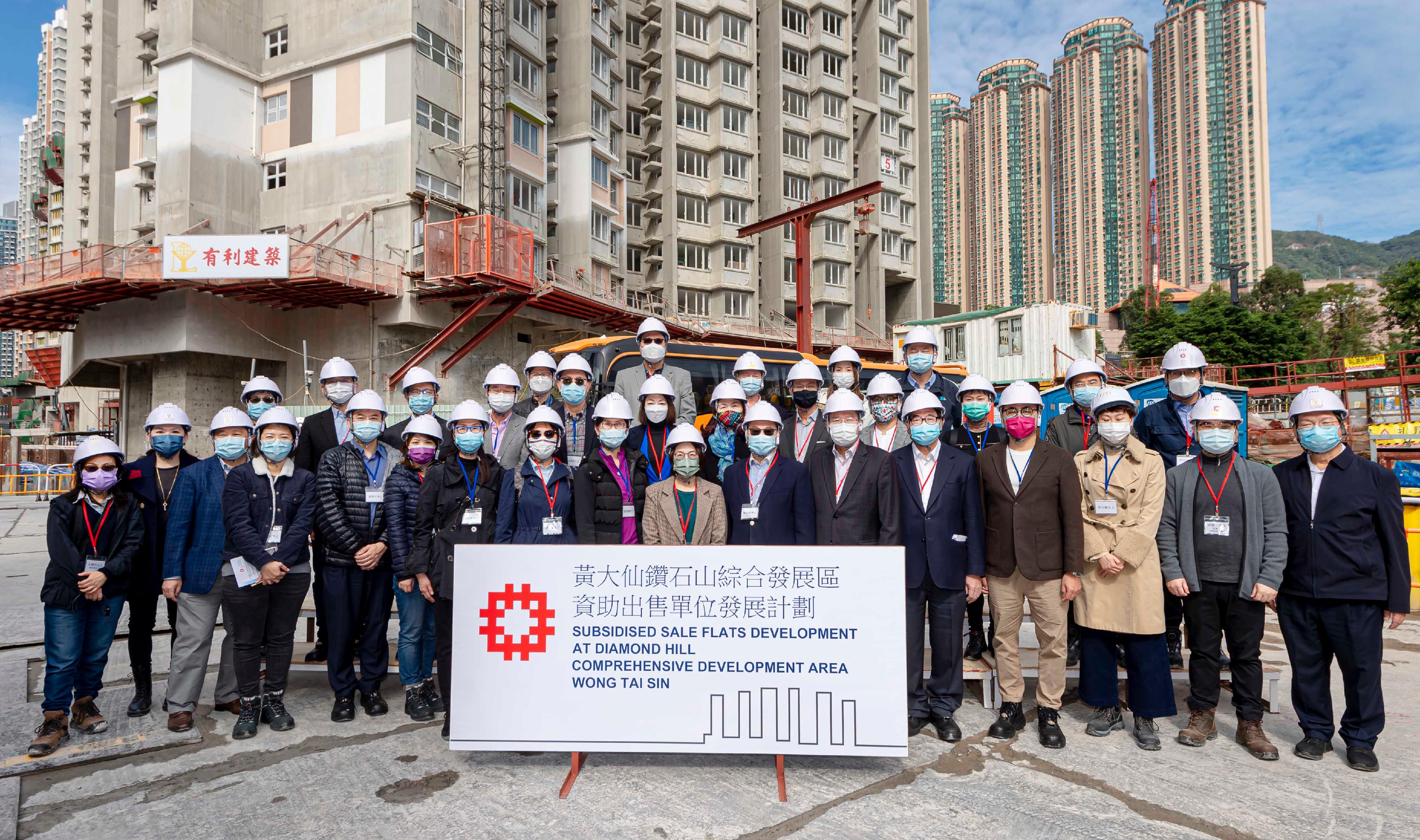 Members of the Hong Kong Housing Authority and members of its Building Committee and Tender Committee paid a visit to the Kai Cheung Court Home Ownership Scheme project at Diamond Hill today (December 23) to learn more about its progress. Photo shows members with Housing Department officials at the site.