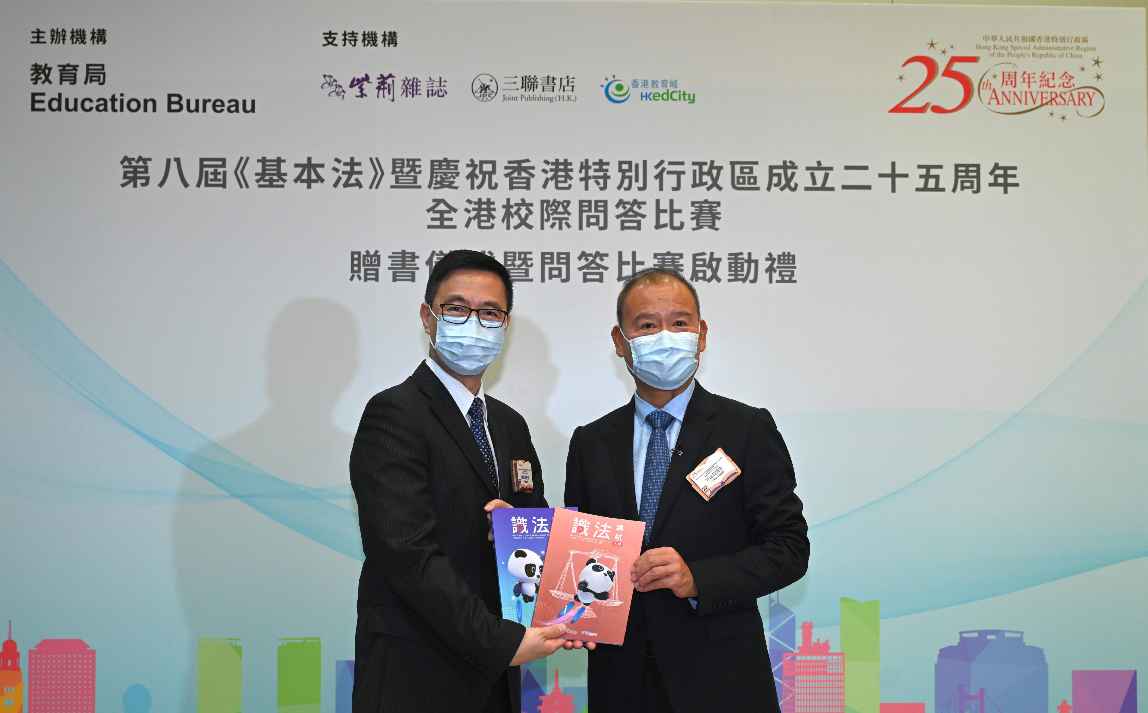 The Secretary for Education, Mr Kevin Yeung (left), receives on behalf of schools "National Laws Applicable to HKSAR: A Student Guide" from Member of the Board of Bauhinia Culture Group Mr Wu Baoan (right) at the 8th Basic Law cum the 25th Anniversary of Establishment of the Hong Kong Special Administrative Region Territory-wide Inter-school Competition Kick-off cum Books Giving Ceremony today (January 5).