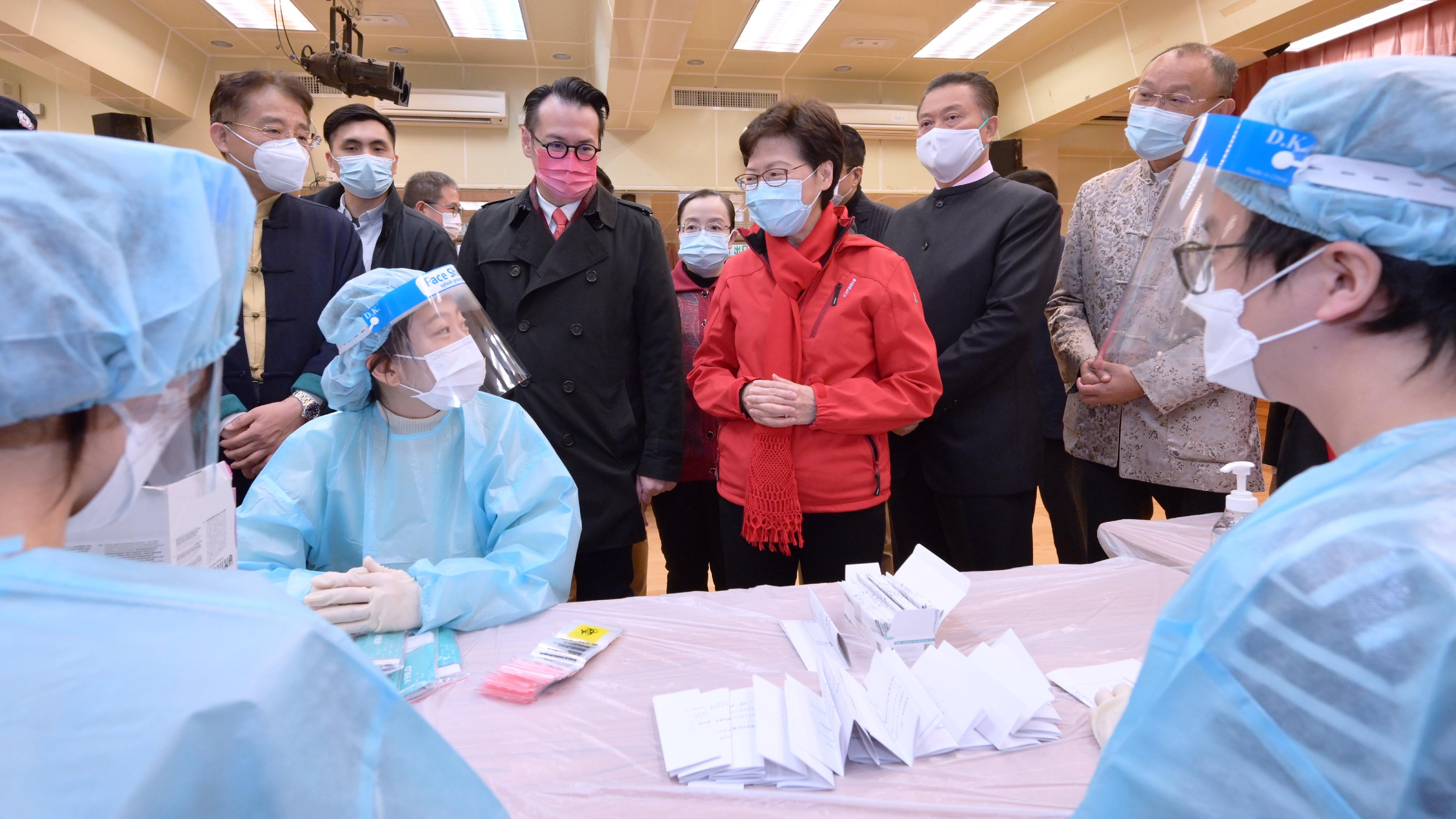 The Chief Executive, Mrs Carrie Lam, visited volunteers helping with the packing of rapid test kits at Kwun Tong Community Centre today (February 2). Photo shows Mrs Lam (third right) chatting with volunteers. Looking on are the District Officer (Kwun Tong), Mr Steve Tse (third left), and the Acting Director of Home Affairs, Miss Vega Wong (centre).