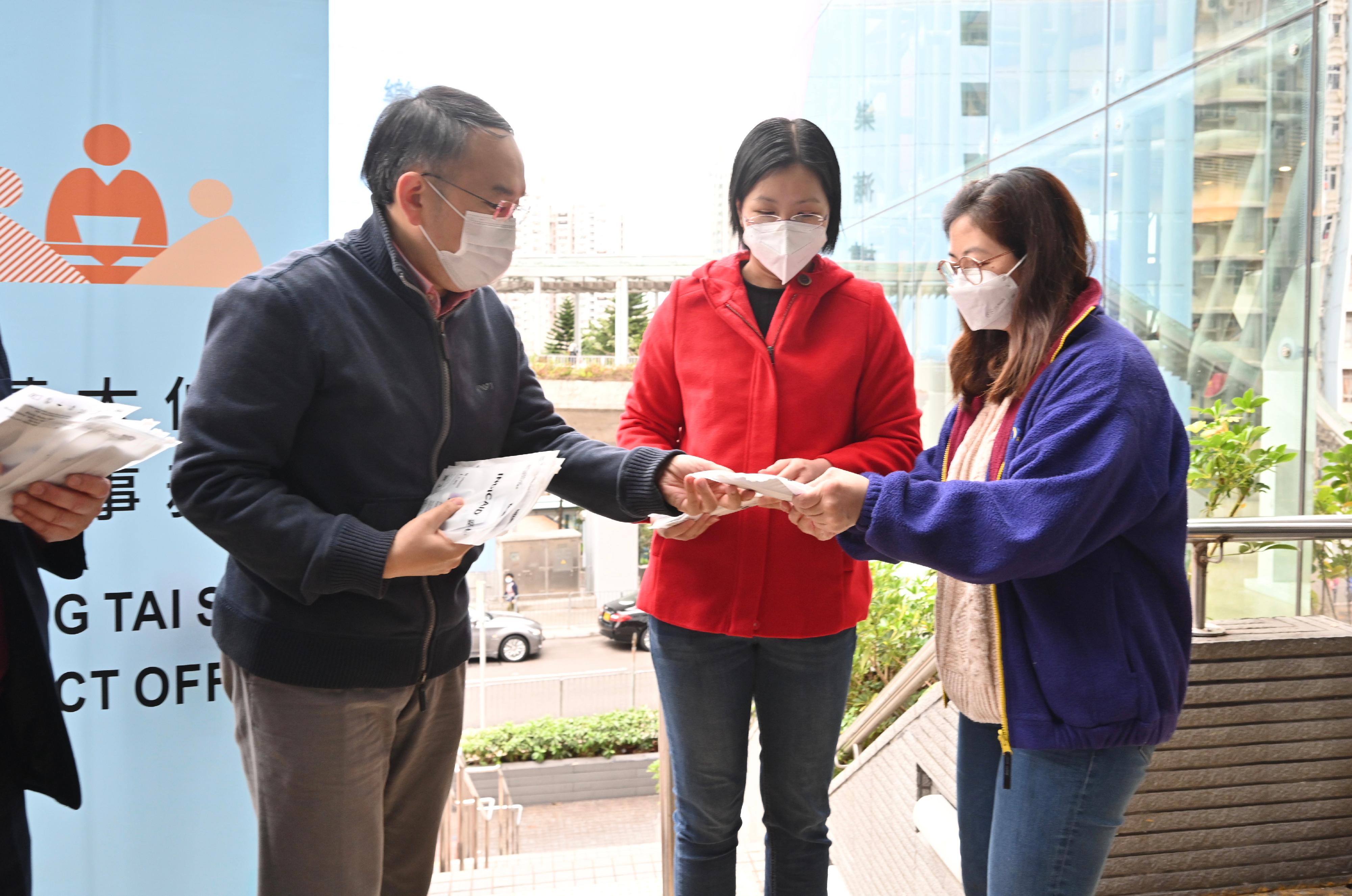 The Secretary for Financial Services and the Treasury, Mr Christopher Hui (first left), distributes COVID-19 rapid test kit at Tsz Wan Shan Shopping Centre today (February 3) and calls on residents to undergo voluntary testing and help fight the virus together.