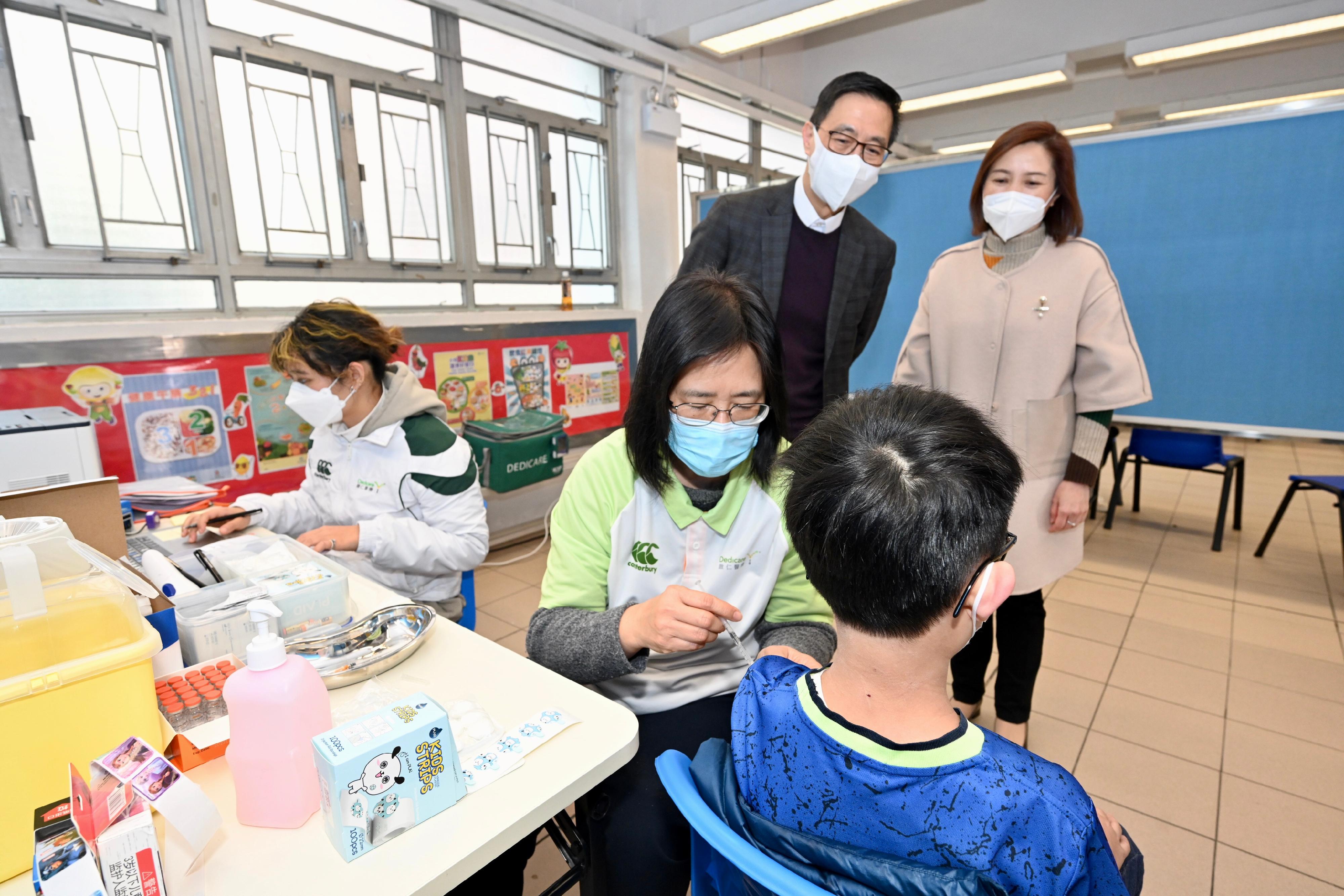 The Secretary for Education, Mr Kevin Yeung, visited Shau Kei Wan Government Primary School today (February 25) to inspect the implementation of the Vaccination Subsidy Scheme School Outreach. Photo shows Mr Yeung (back row, left), accompanied by the Headmistress, Ms Leung Ching-yee (back row, right), observing a student receiving his COVID-19 vaccination.