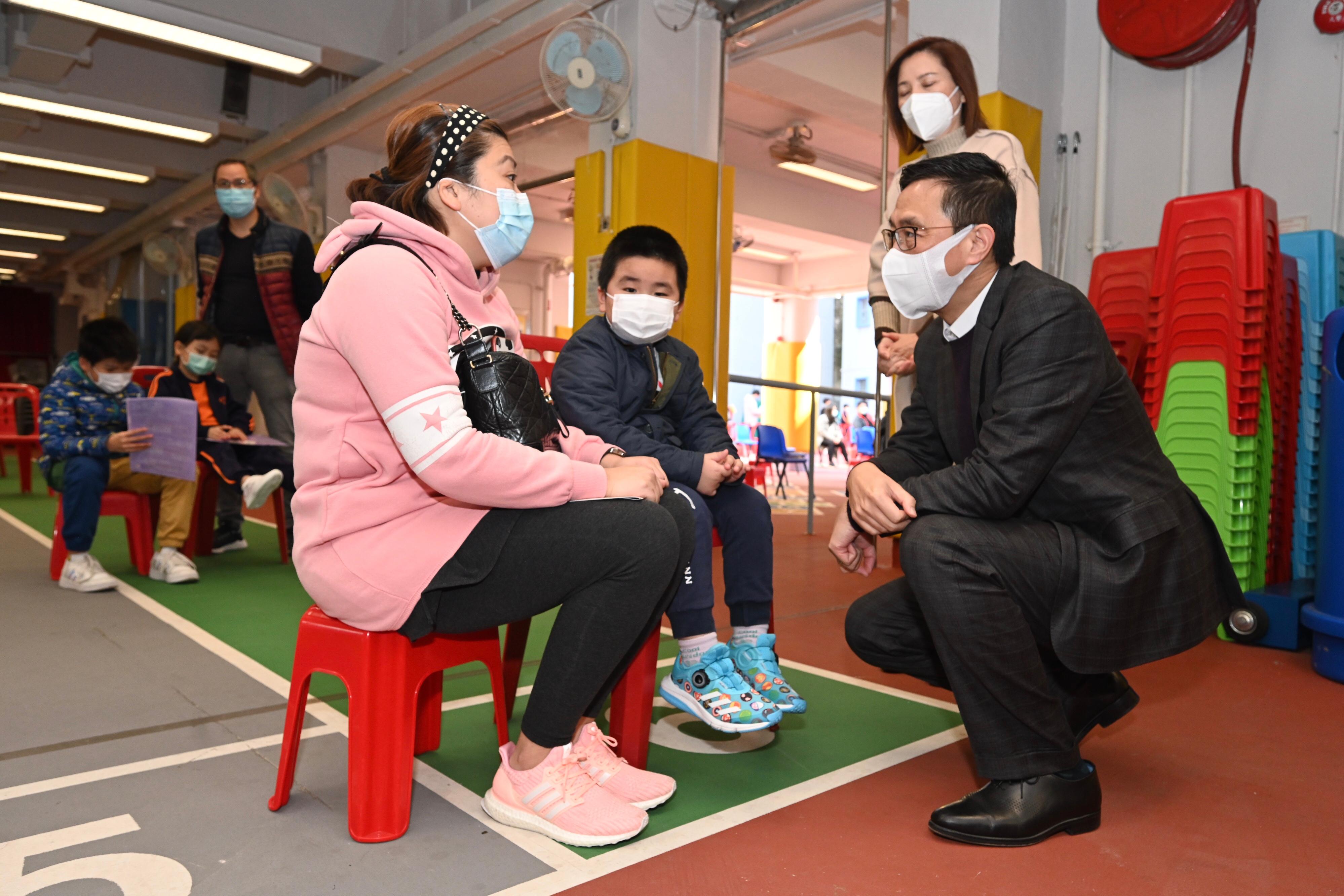 The Secretary for Education, Mr Kevin Yeung, visited Shau Kei Wan Government Primary School today (February 25) to inspect the implementation of the Vaccination Subsidy Scheme School Outreach. Picture shows Mr Yeung talking to a parent and a student.