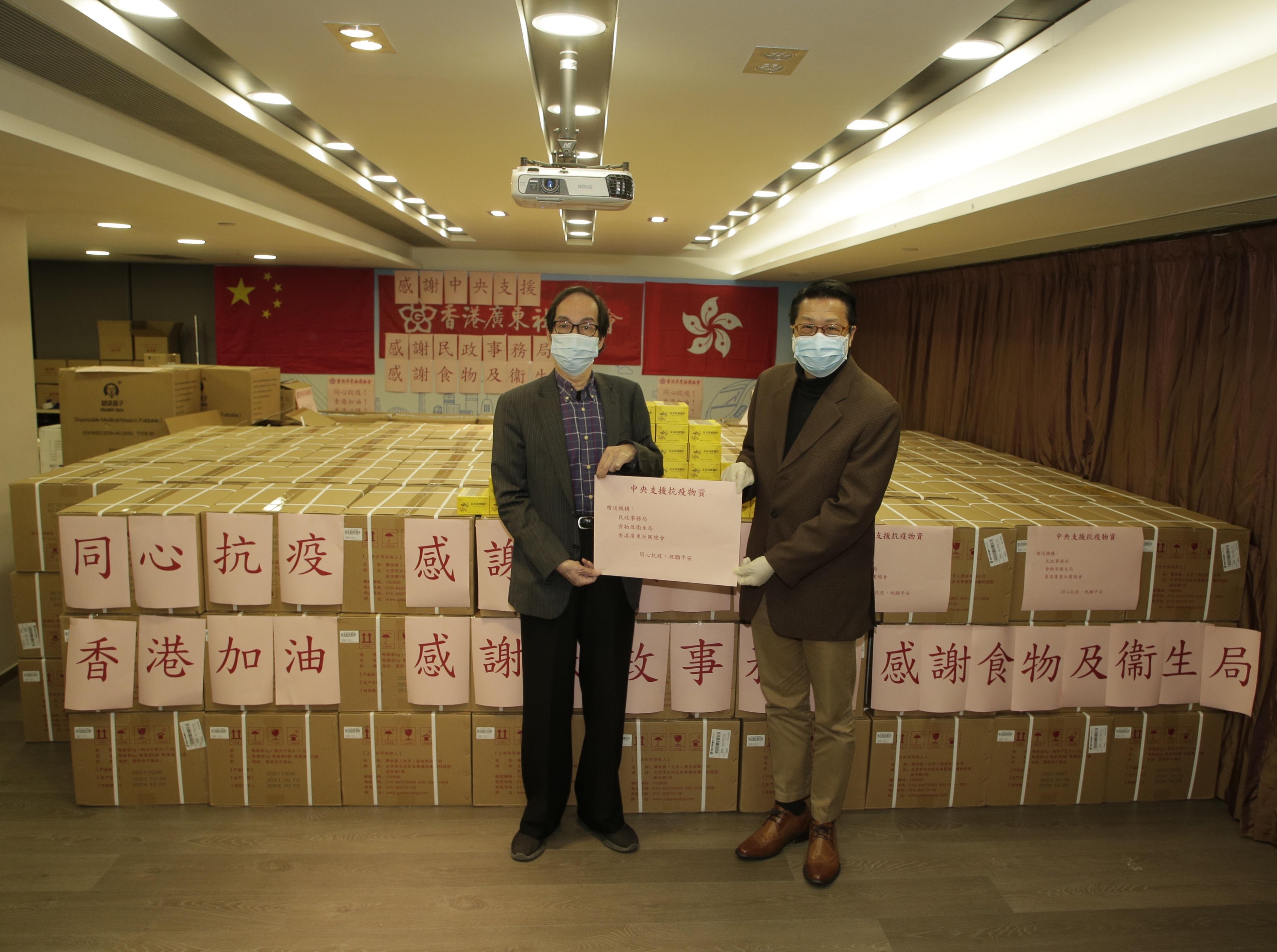 The Acting Secretary for Home Affairs, Mr Jack Chan, today (February 26) joined major organisations separately to distribute anti-epidemic supplies in several districts. Photo shows Mr Chan (right) presenting 50 000 boxes of  "Jinhua Qinggan Keli" donated by the Central Government to the Federation of Hong Kong Guangdong Community Organisations for further distribution to people in need.