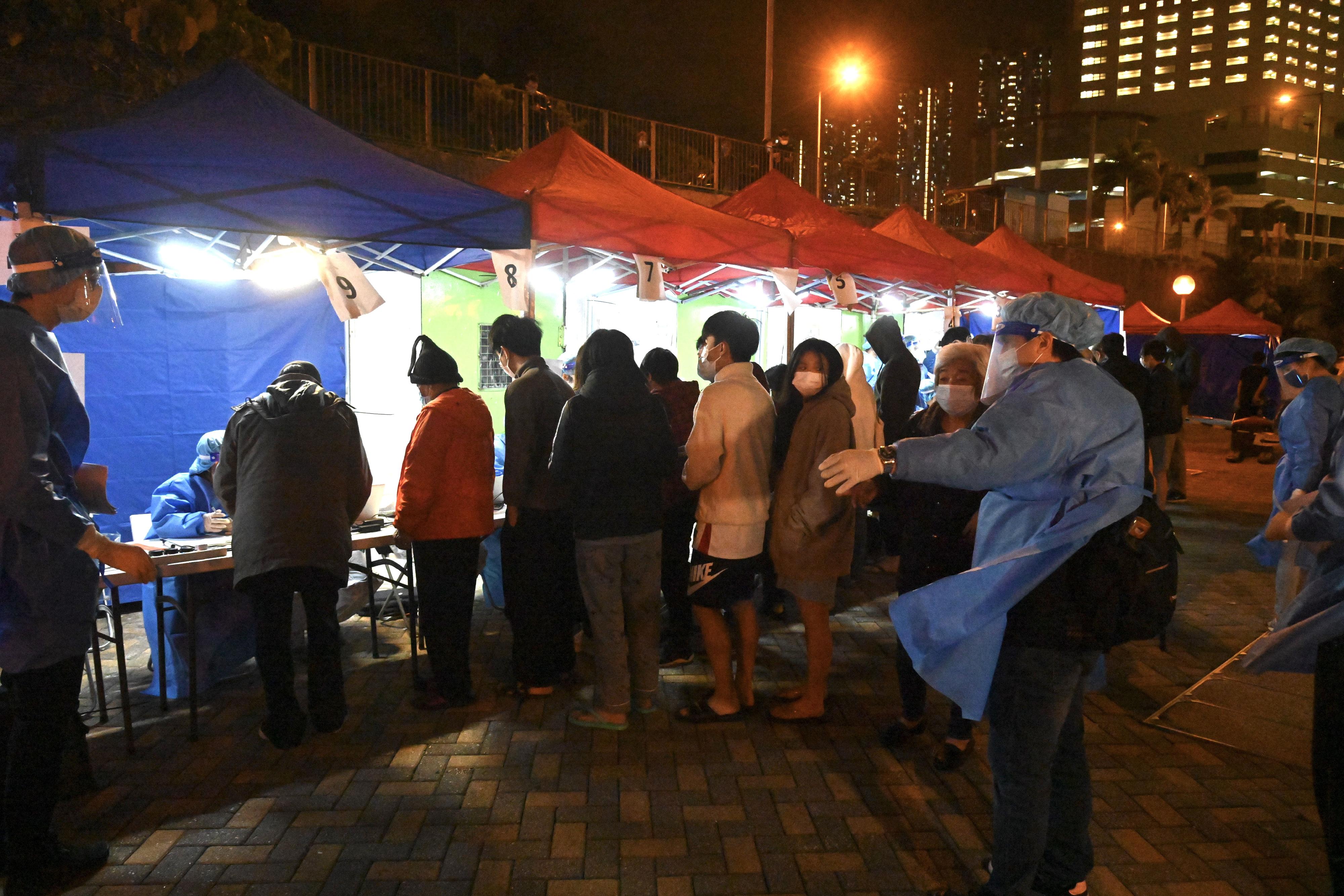 The Census and Statistics Department (C&SD) co-ordinated and conducted a "restriction-testing declaration" and compulsory testing notice operation in respect of a specified "restricted area" in Sau Yin House, Sau Mau Ping Estate, Kwun Tong, last night (February 28). Photo shows C&SD staff members maintaining order during the operation.