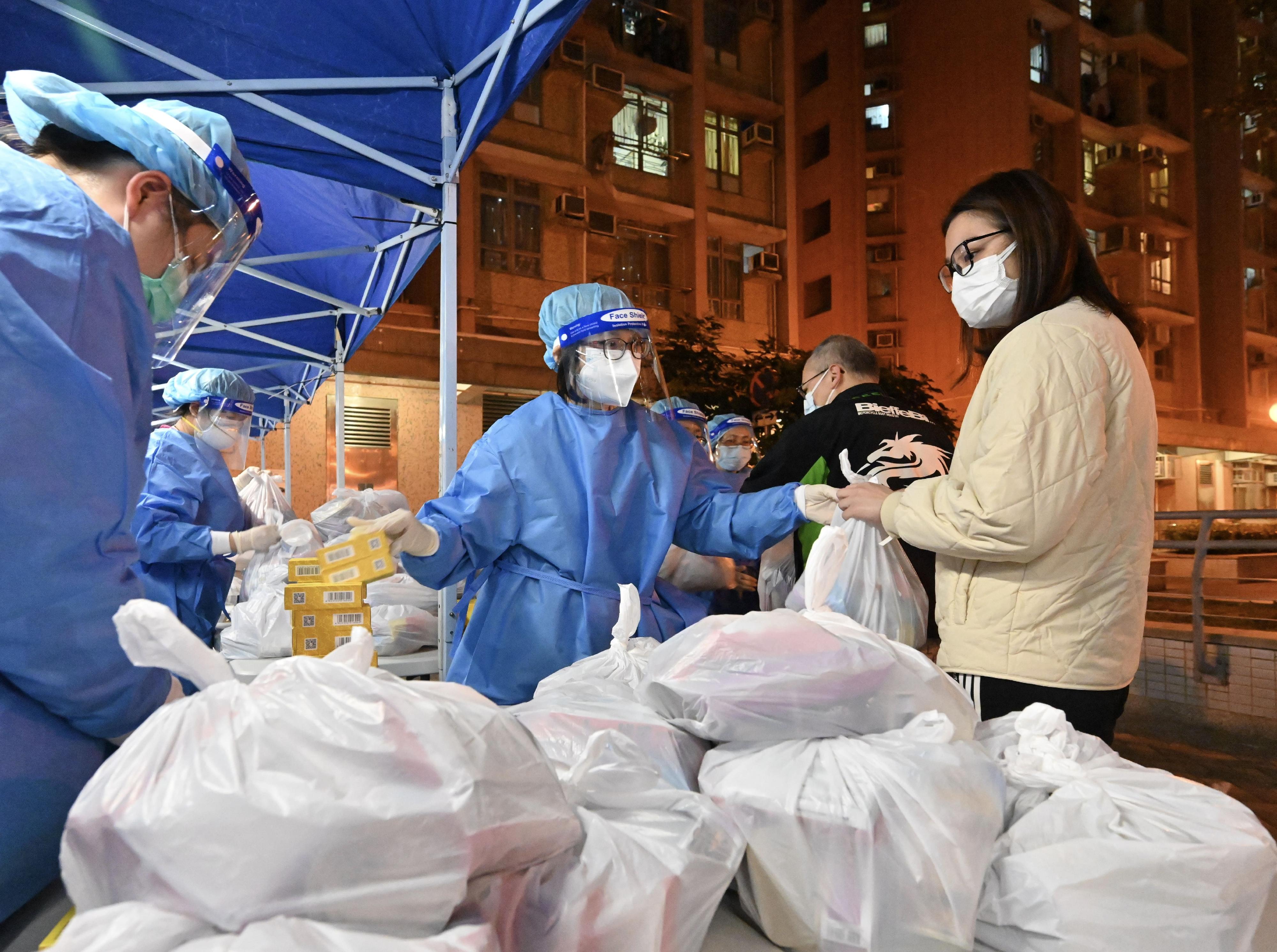 The Census and Statistics Department (C&SD) co-ordinated and conducted a "restriction-testing declaration" and compulsory testing notice operation in respect of a specified "restricted area" in Sau Yin House, Sau Mau Ping Estate, Kwun Tong, last night (February 28). Photo shows C&SD staff members delivering anti-epidemic supplies to residents.