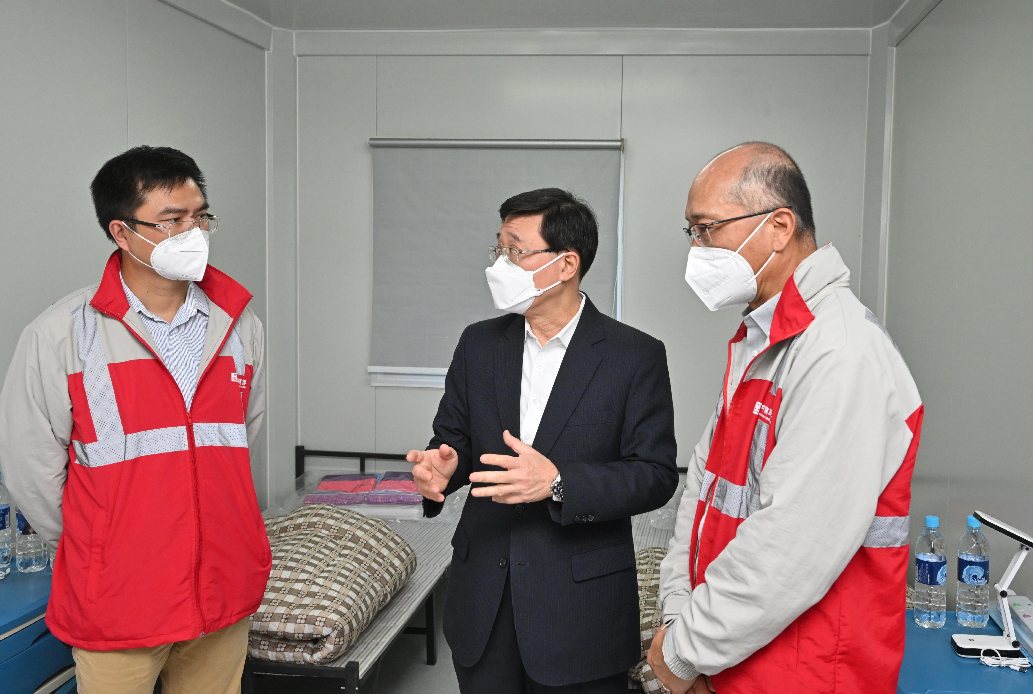 The Chief Secretary for Administration, Mr John Lee, today (March 1) visited the community isolation facilities constructed with the support of the Central Government in Tsing Yi. Photo shows Mr Lee (centre) receiving a briefing from staff members of the contractor on the facilities.