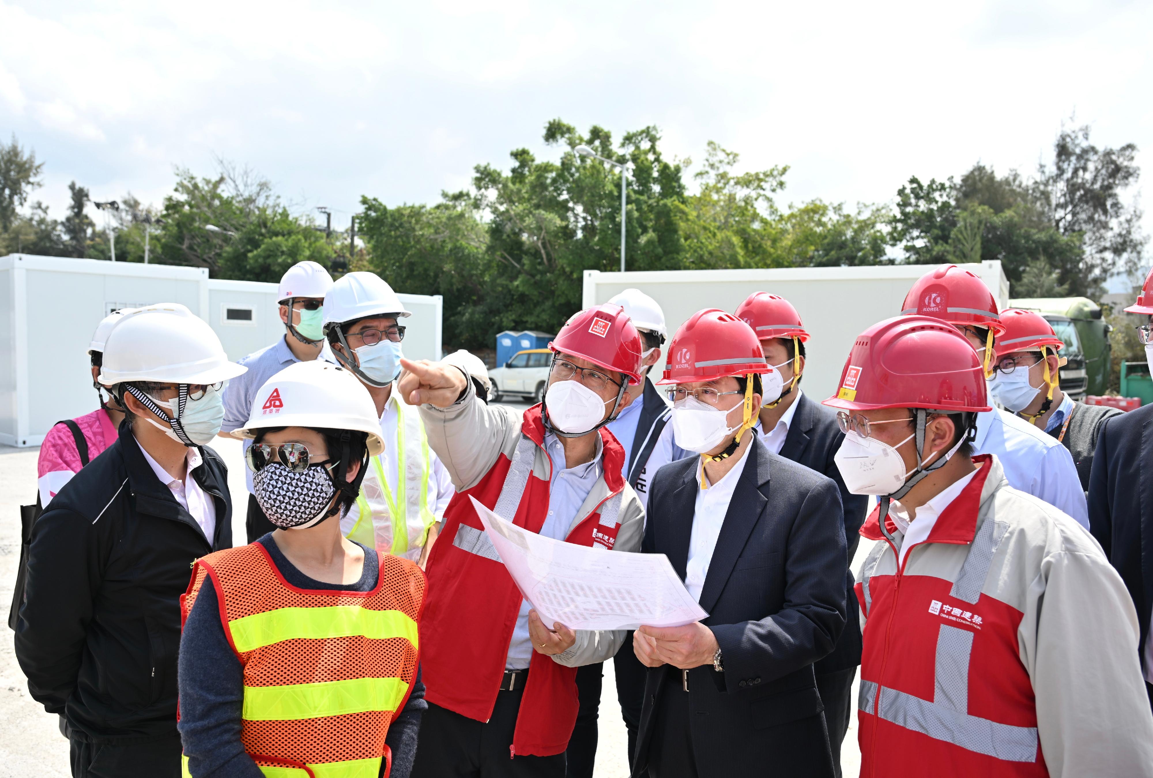 The Chief Secretary for Administration, Mr John Lee, visited the community isolation and treatment facilities constructed with the support of the Central Government in Tsing Yi, Lok Ma Chau and San Tin today (March 1). Photo shows Mr Lee (front row, second right), accompanied by the Secretary for Development, Mr Michael Wong (second row, second left), and the Director of Architectural Services, Ms Winnie Ho (front row, first left), receiving a briefing from a representative of the contractor on the construction of facilities in San Tin.