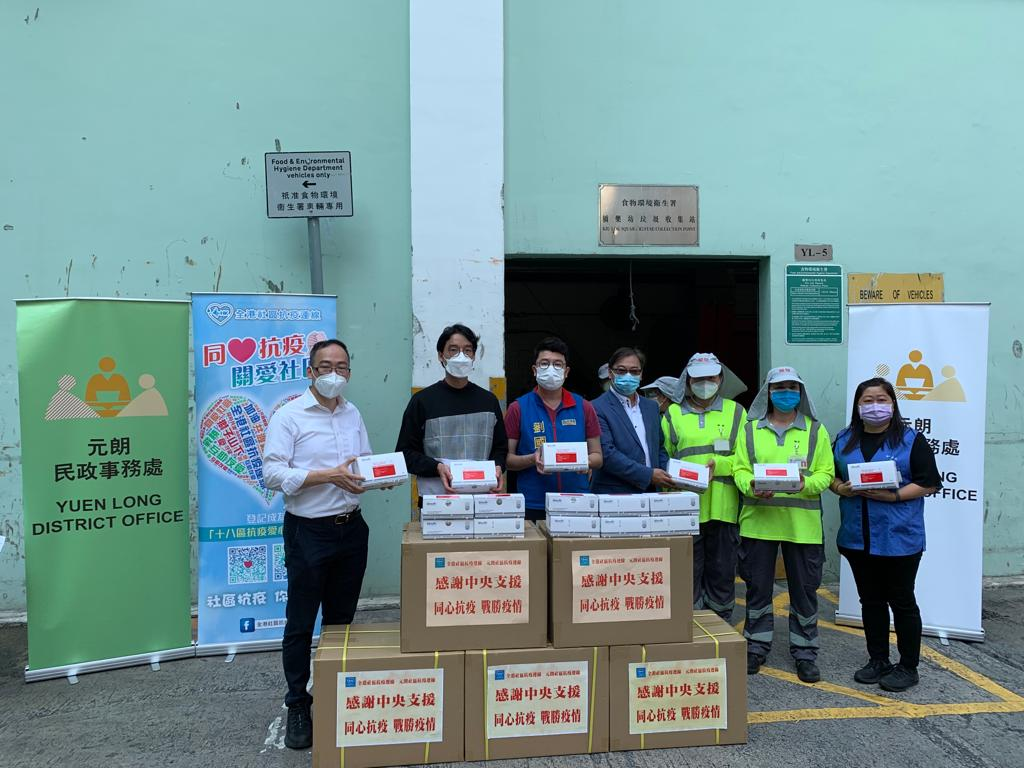 元朗民政事務專員胡天祐（左二）三月三日在元朗大橋垃圾站向清潔員工派發中央援港的快速測試套裝。
