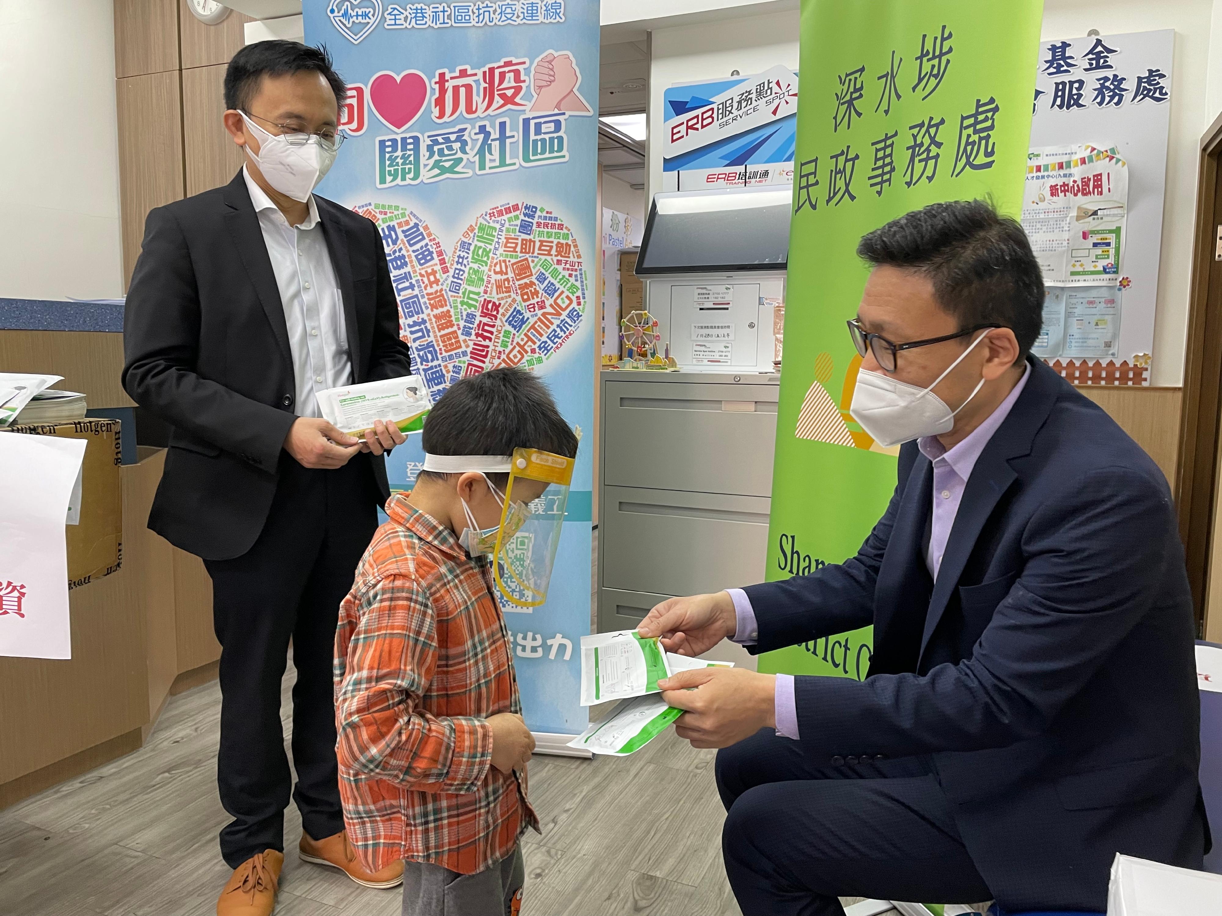 The Sham Shui Po District Office distributed rapid test kits supplied by the Central Government in the district through district organisations on March 3. Rapid test kits and other supplies were particularly distributed to grassroot families such as new arrivals and households living in subdivided flats. Photo shows the District Officer (Sham Shui Po), Mr Paul Wong (first right), distributing rapid test kits to a child from a household living in a subdivided flat. 

