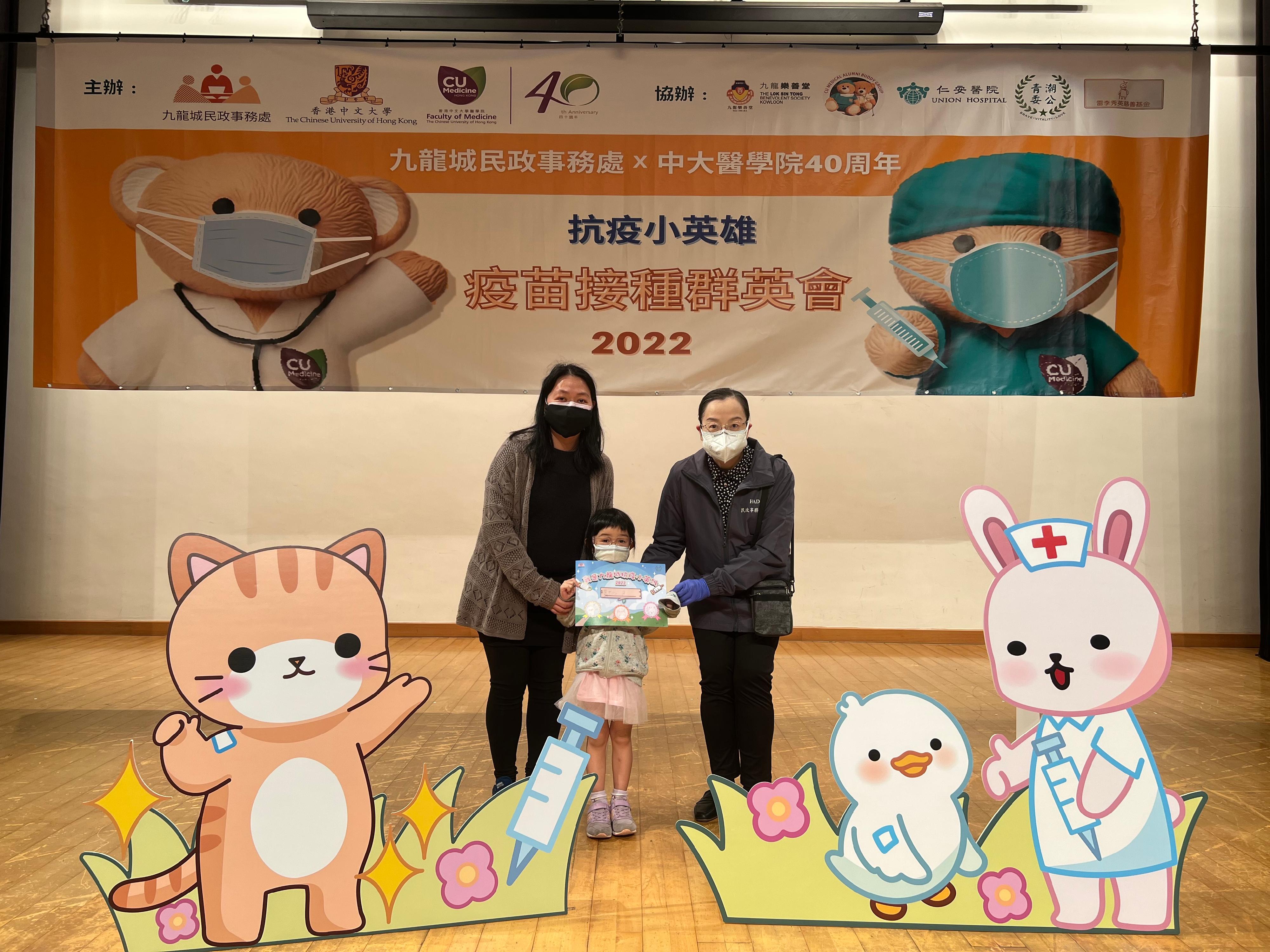 Acting Director of Home Affairs, Miss Vega Wong, officiated at the presentation ceremony of a community vaccination event for children known as "I am the Little Anti-pandemic Hero" organised by the Kowloon City District Office held at the Hung Hom Community Hall today (March 6). Picture shows Miss Wong (right) presenting a certificate to a child (centre) who has been vaccinated.
