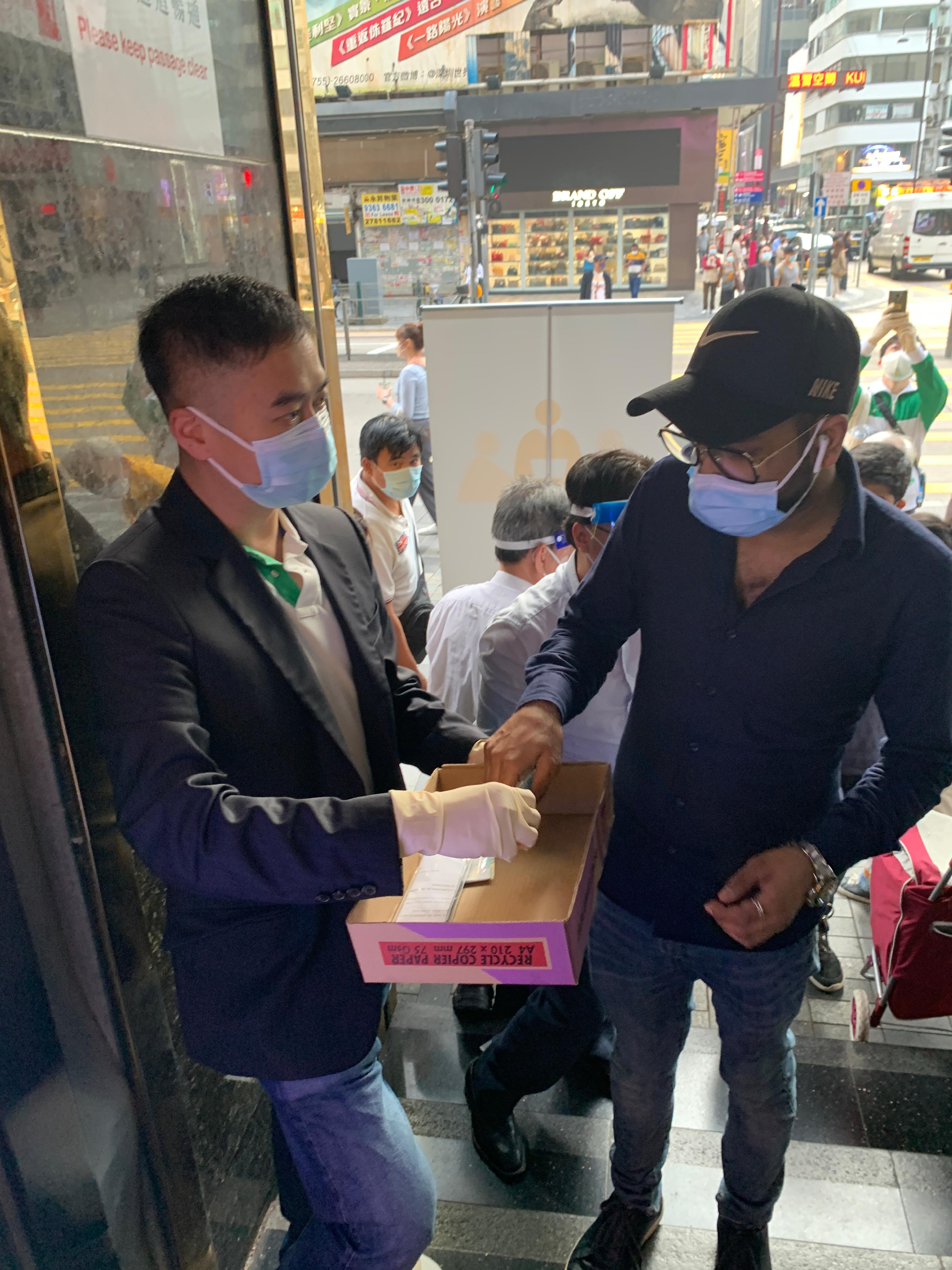 Over the past few days, the Yau Tsim Mong District Office has been distributing rapid test kits to residents of buildings in Yau Tsim Mong District where more ethnic minorities reside. Photo shows the District Officer (Yau Tsim Mong), Mr Edward Yu (left), distributing rapid test kits to residents of Chungking Mansions on March 5.