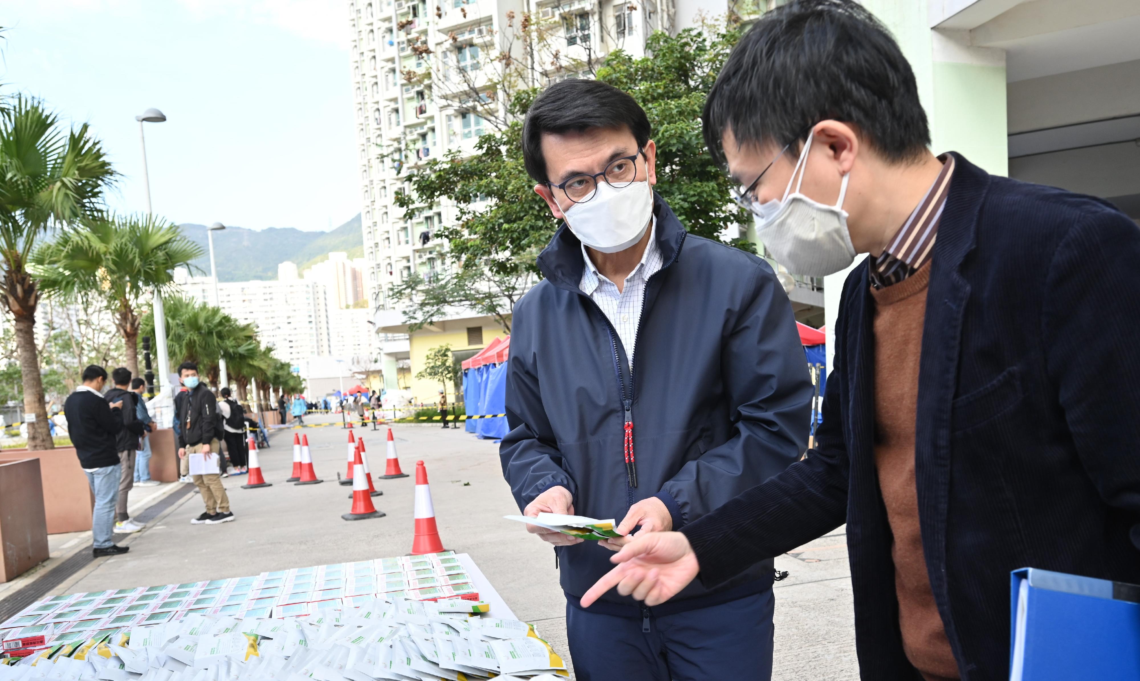 The Secretary for Commerce and Economic Development, Mr Edward Yau, yesterday (March 7) inspected the "restriction-testing declaration" (RTD) operation conducted by the Trade and Industry Department in the "restricted area" at Yuet Ching House, Kai Ching Estate, Kowloon City. Photo shows Mr Yau (left) being briefed on the RTD operation by the Deputy Director-General of Trade and Industry, Mr Anson Lai (right).